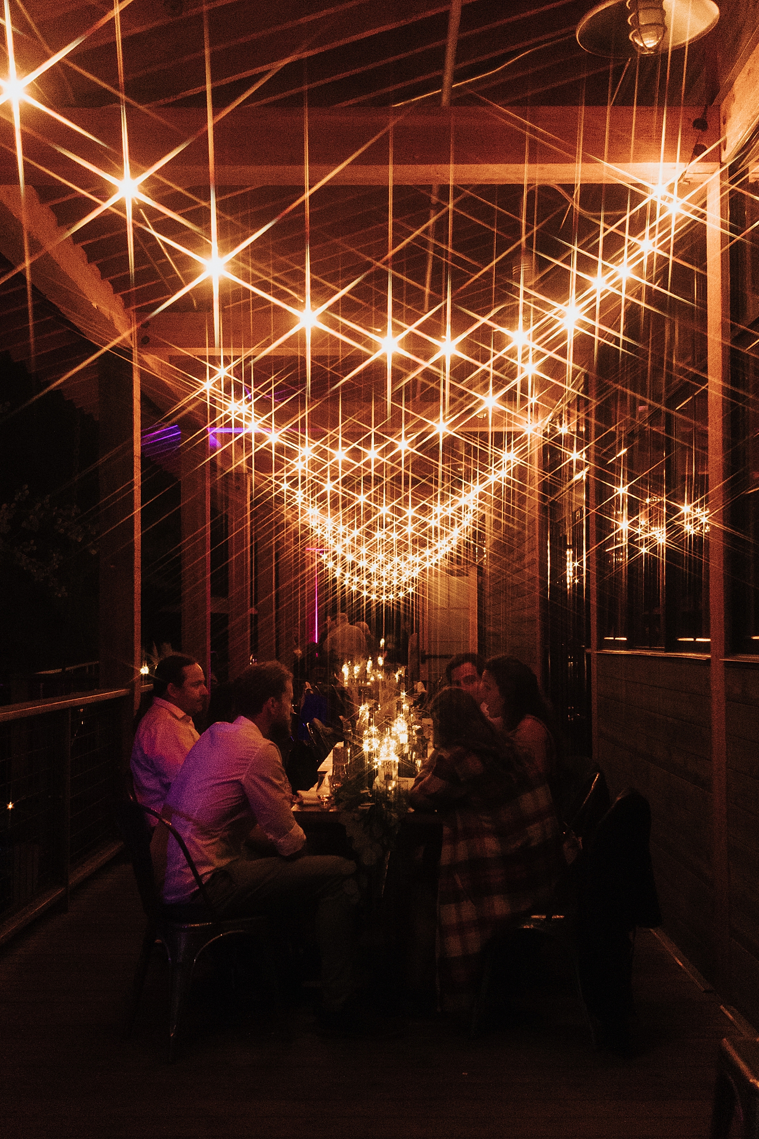 guests mingle at table under twinkling lights by Destination wedding photographer 