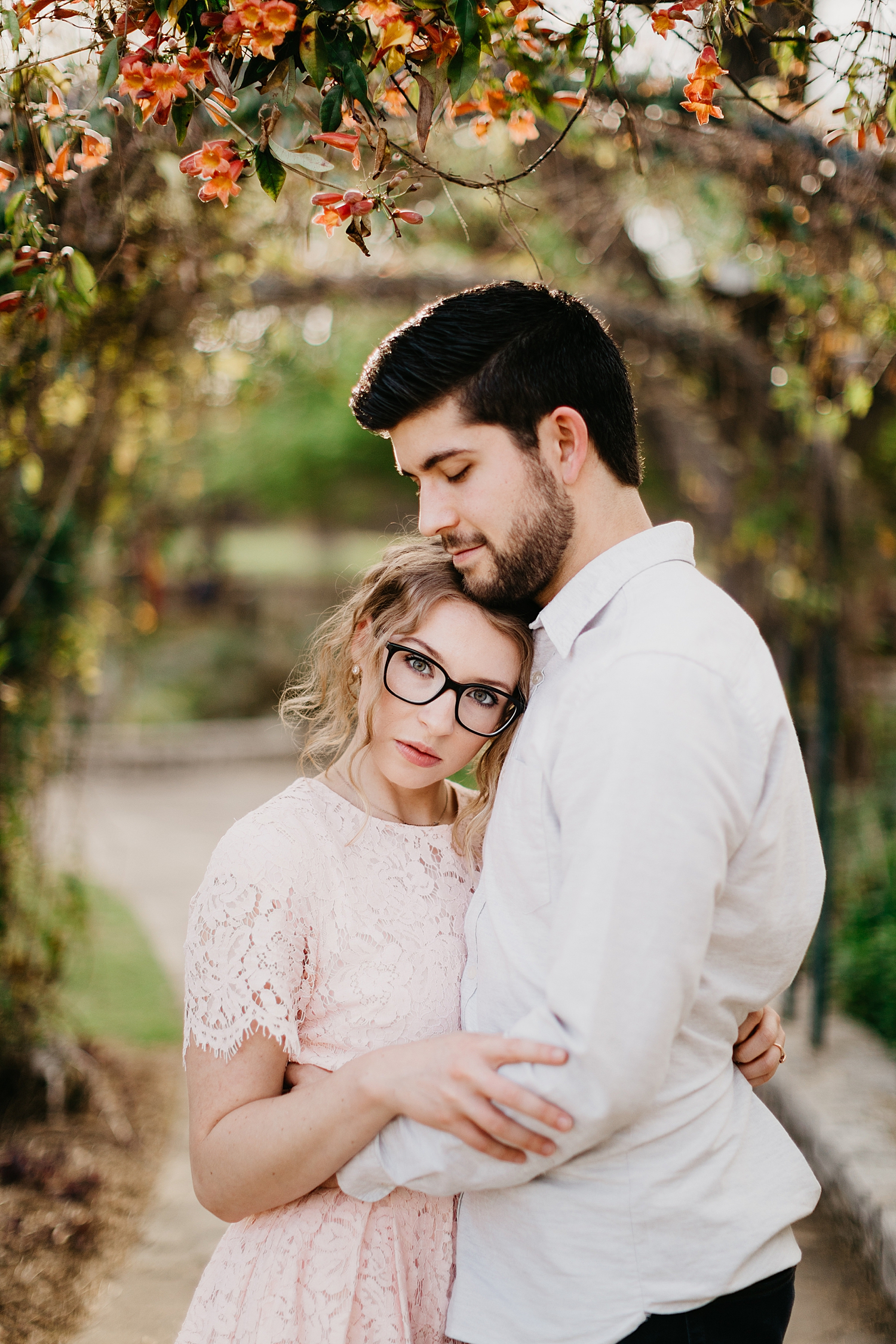 husband holds woman in pink lace dress by Nicole Aston Photography