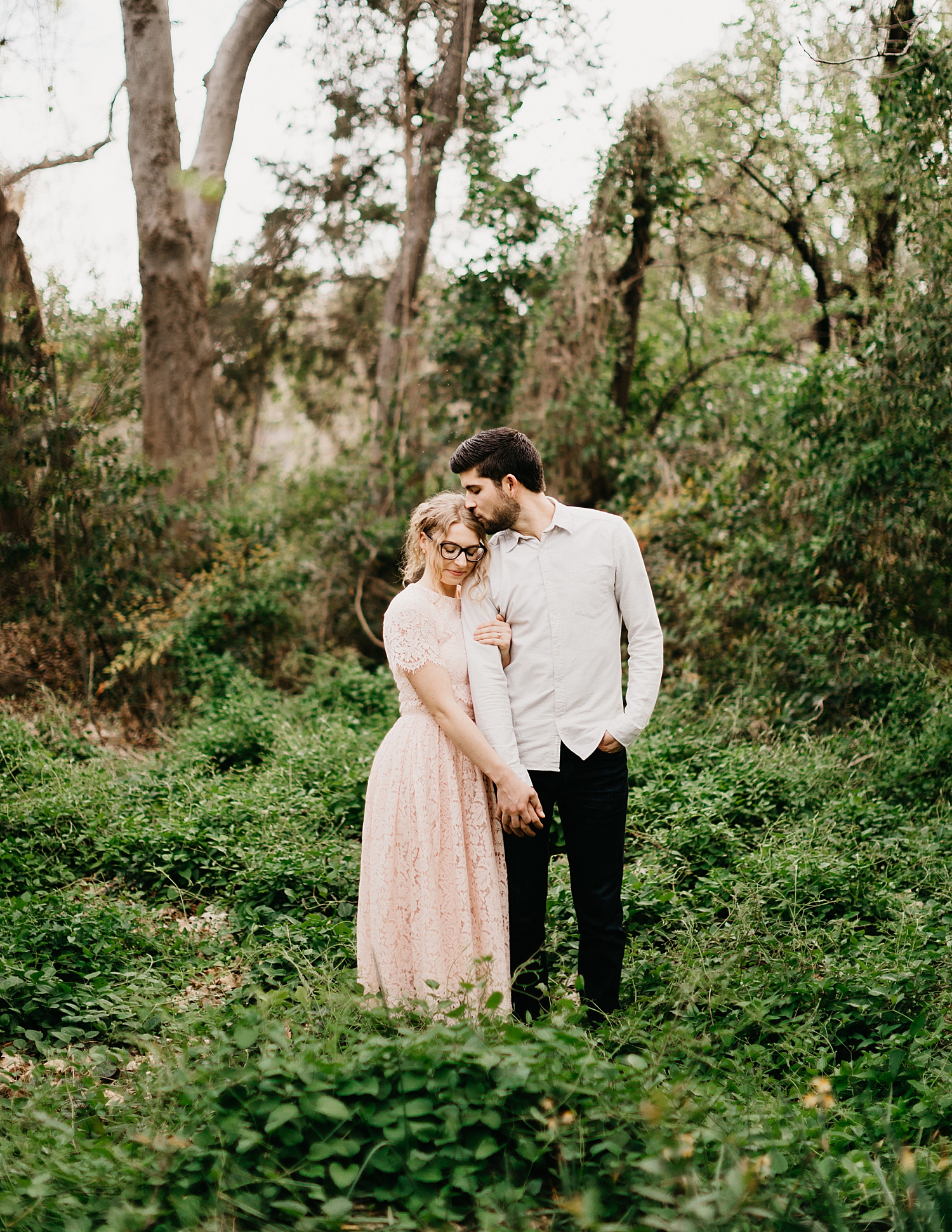 man kisses wife's head in botanic gardens for Downtown DFW Couples Session