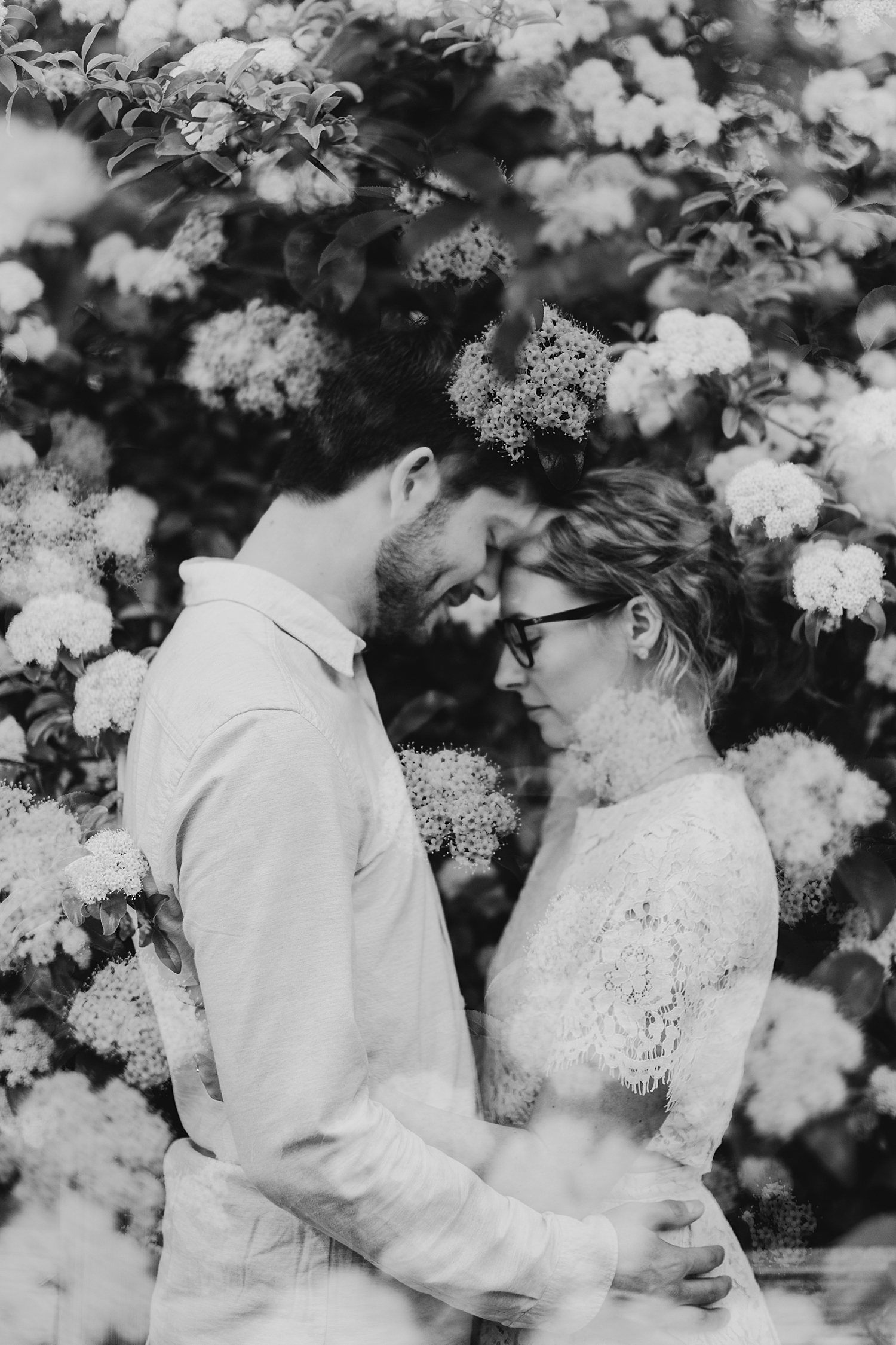 husband and wife put foreheads together under flowers by Destination Wedding Photographer
