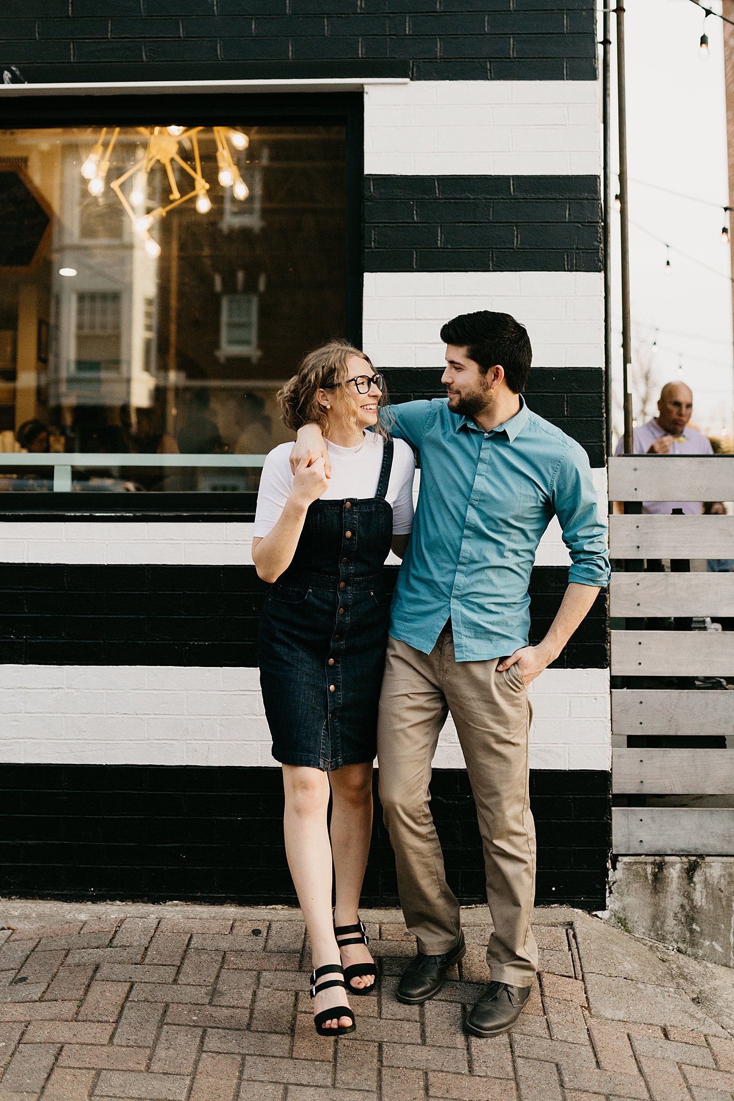 woman wearing overall dress walks with man for Downtown DFW Couples Session