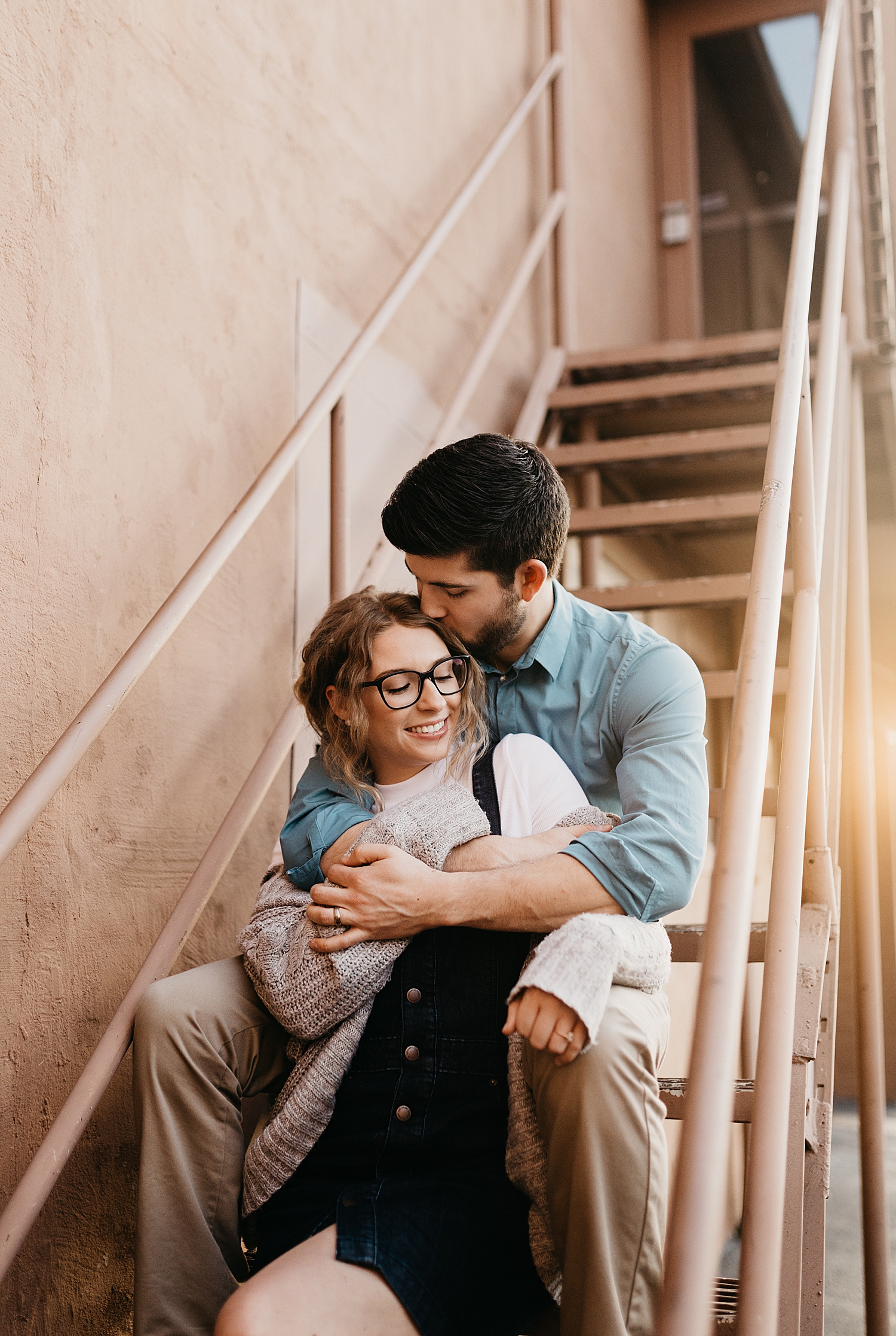 husband kisses wife's temple on staircase by Nicole Aston Photography