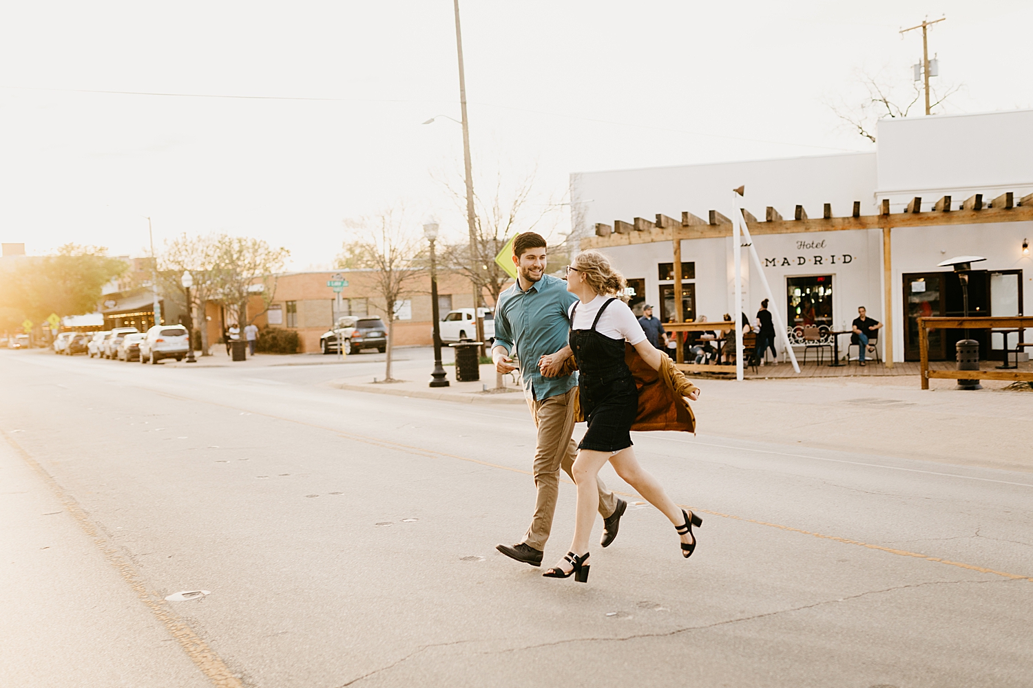 husband and wife run across the street in city by Nicole Aston Photography