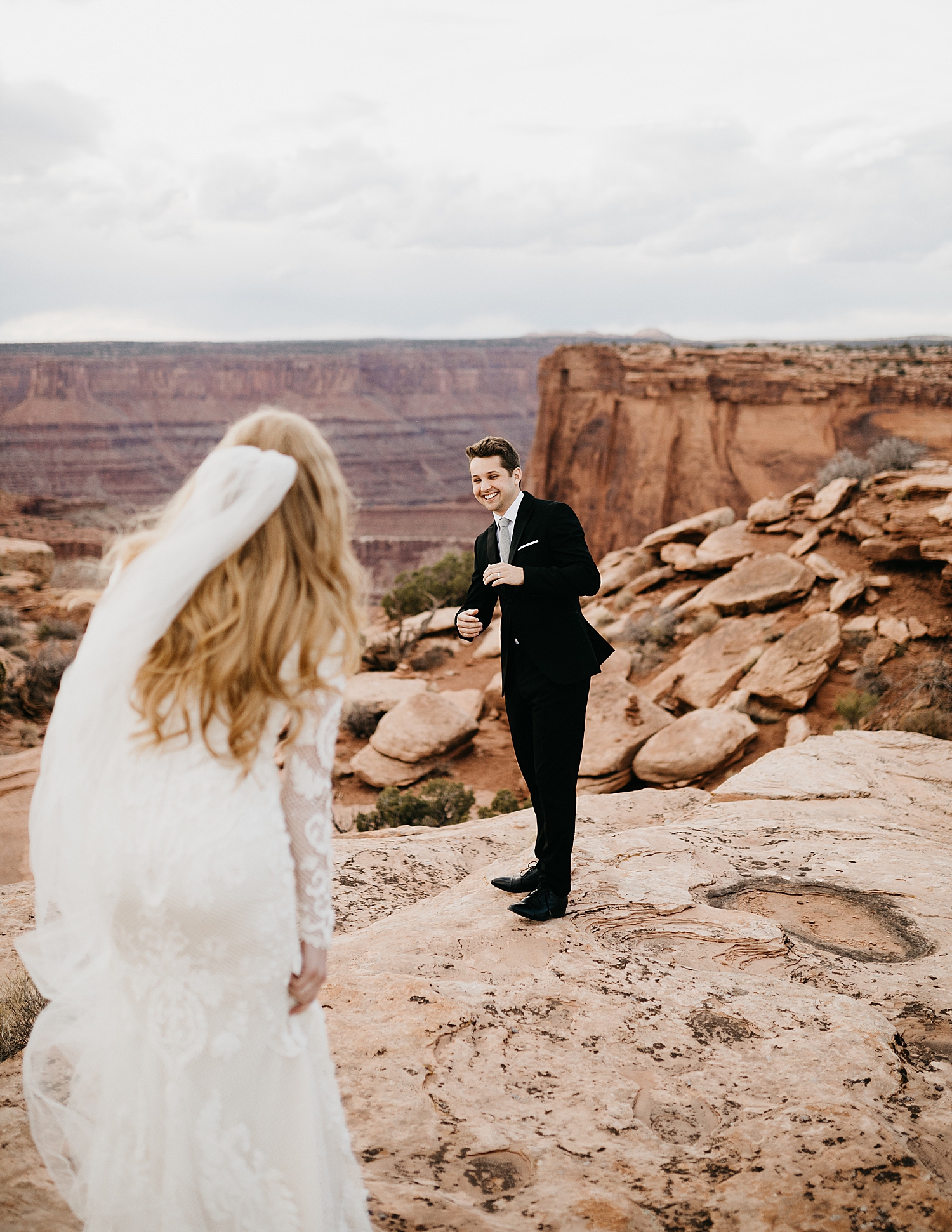 groom smiles in delight at first look on cliffside by Nicole Aston Photography