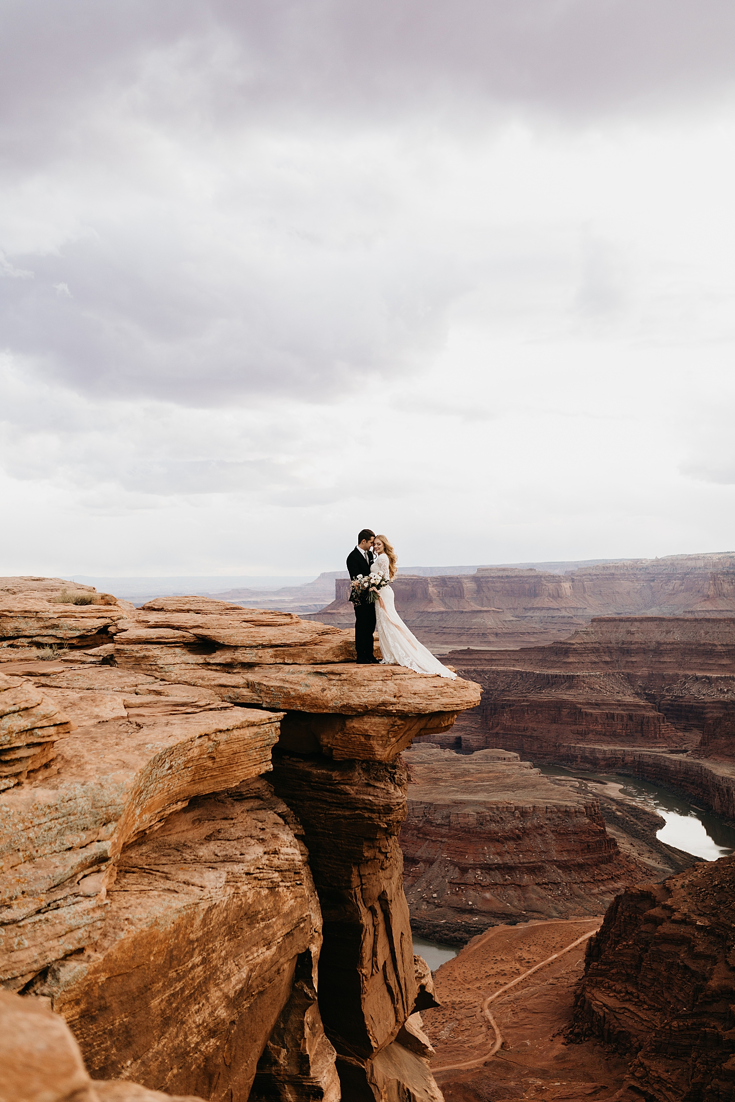 engaged couple stand in formal attire on cliffside by Destination wedding photographer 