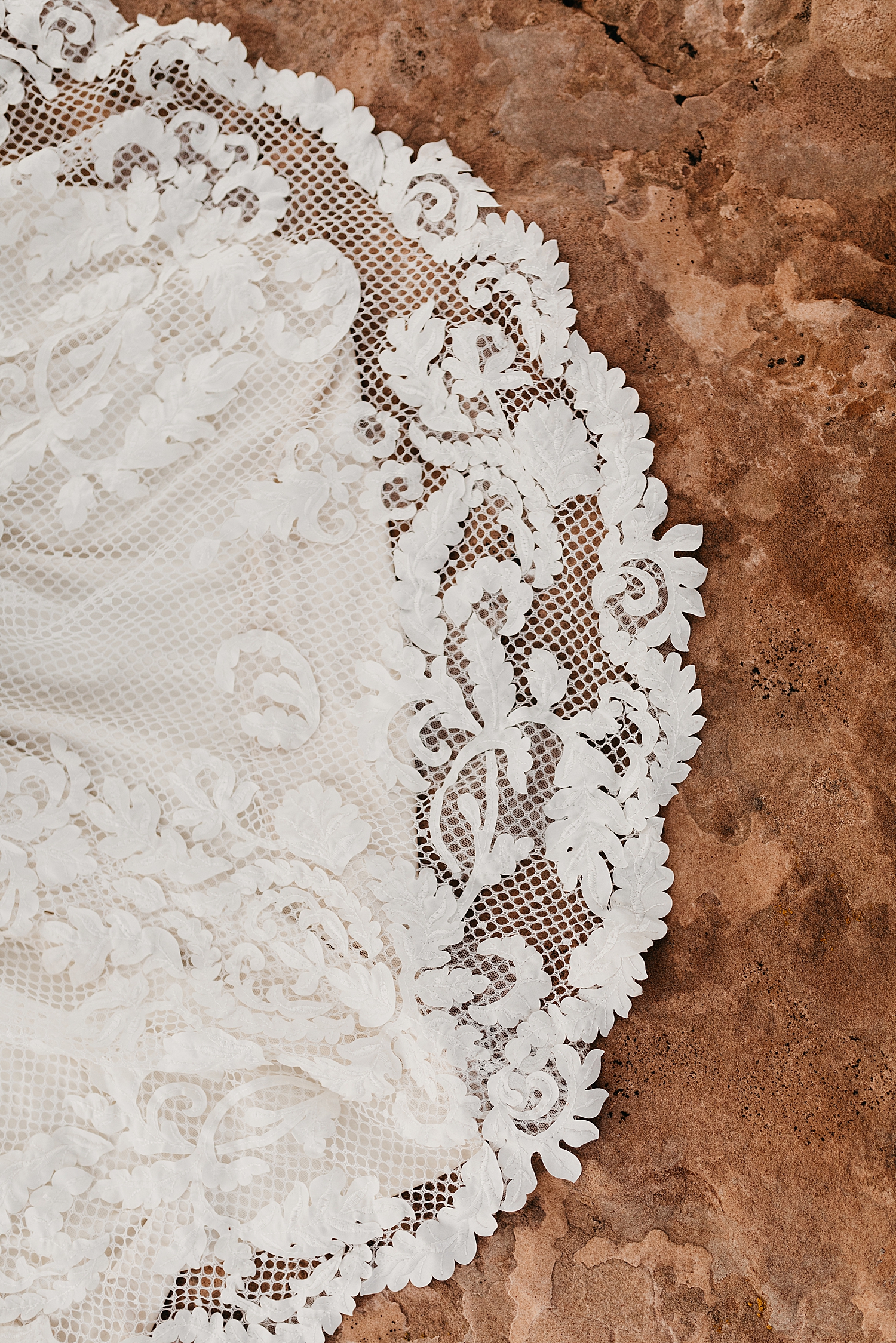 wedding gown lace lying over red rock by Destination wedding photographer 
