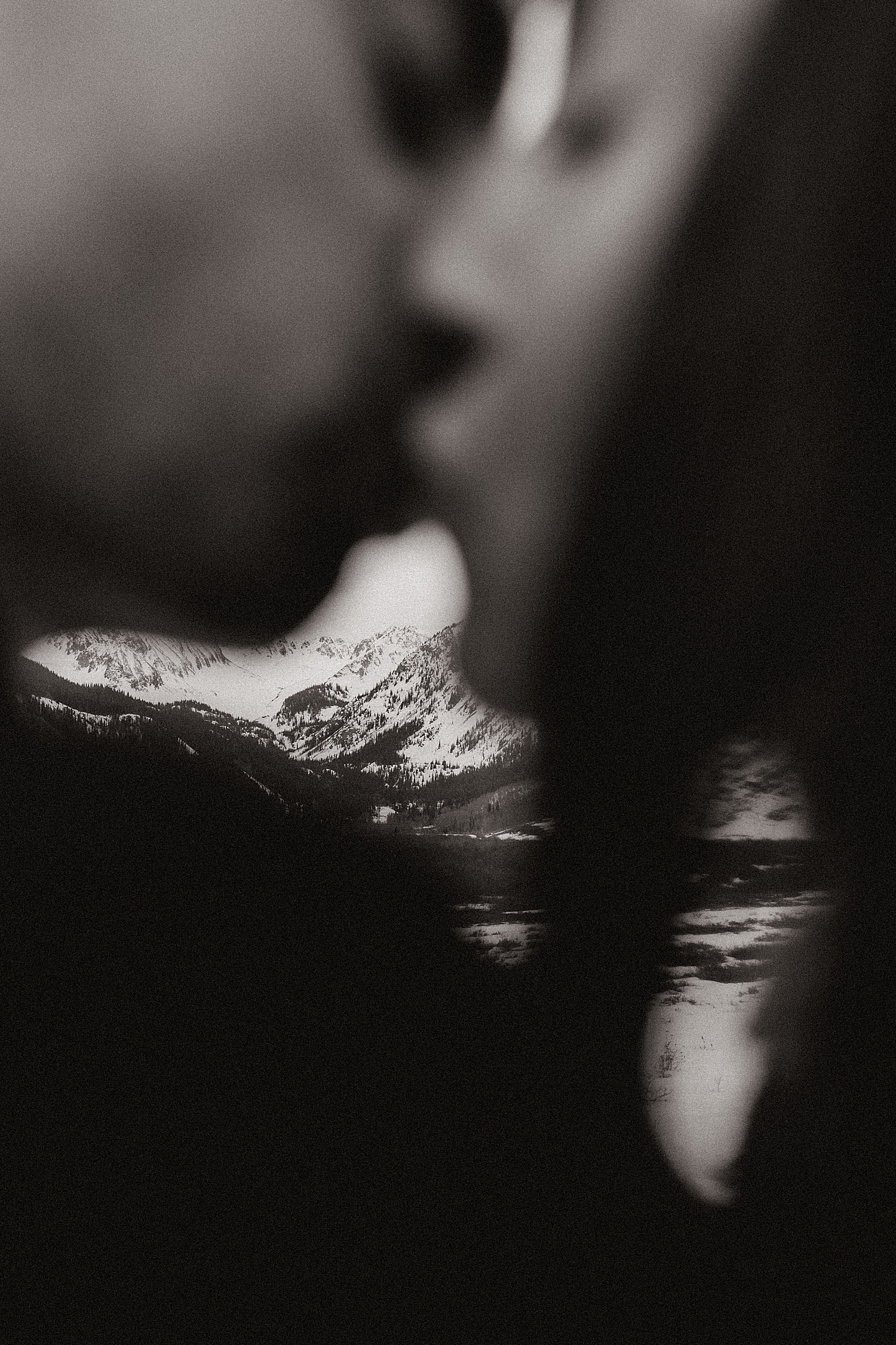 man and woman kiss with mountains in backdrop by Nicole Easton Photo