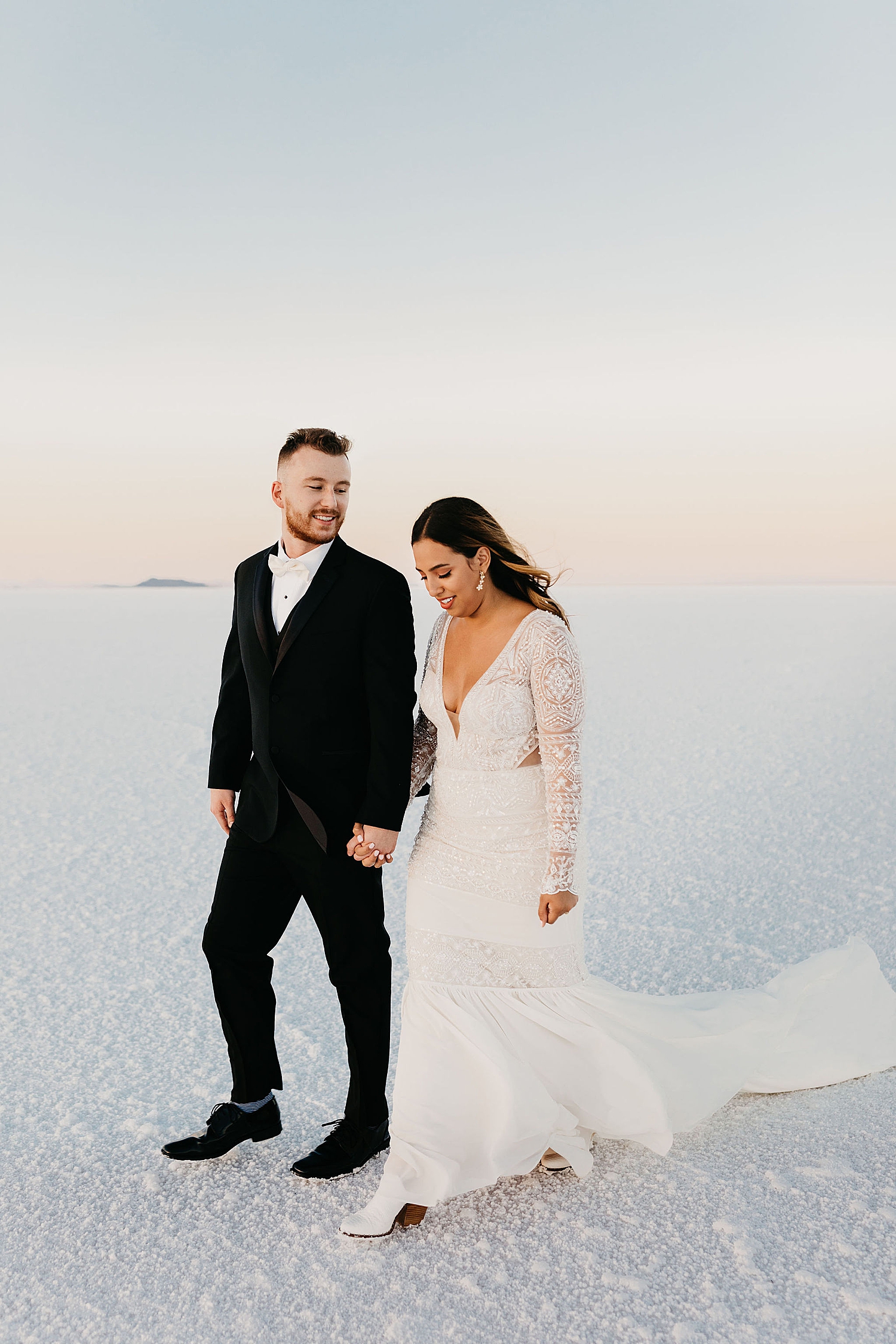 couple walks together across salt flats for First Look + Bridal Session