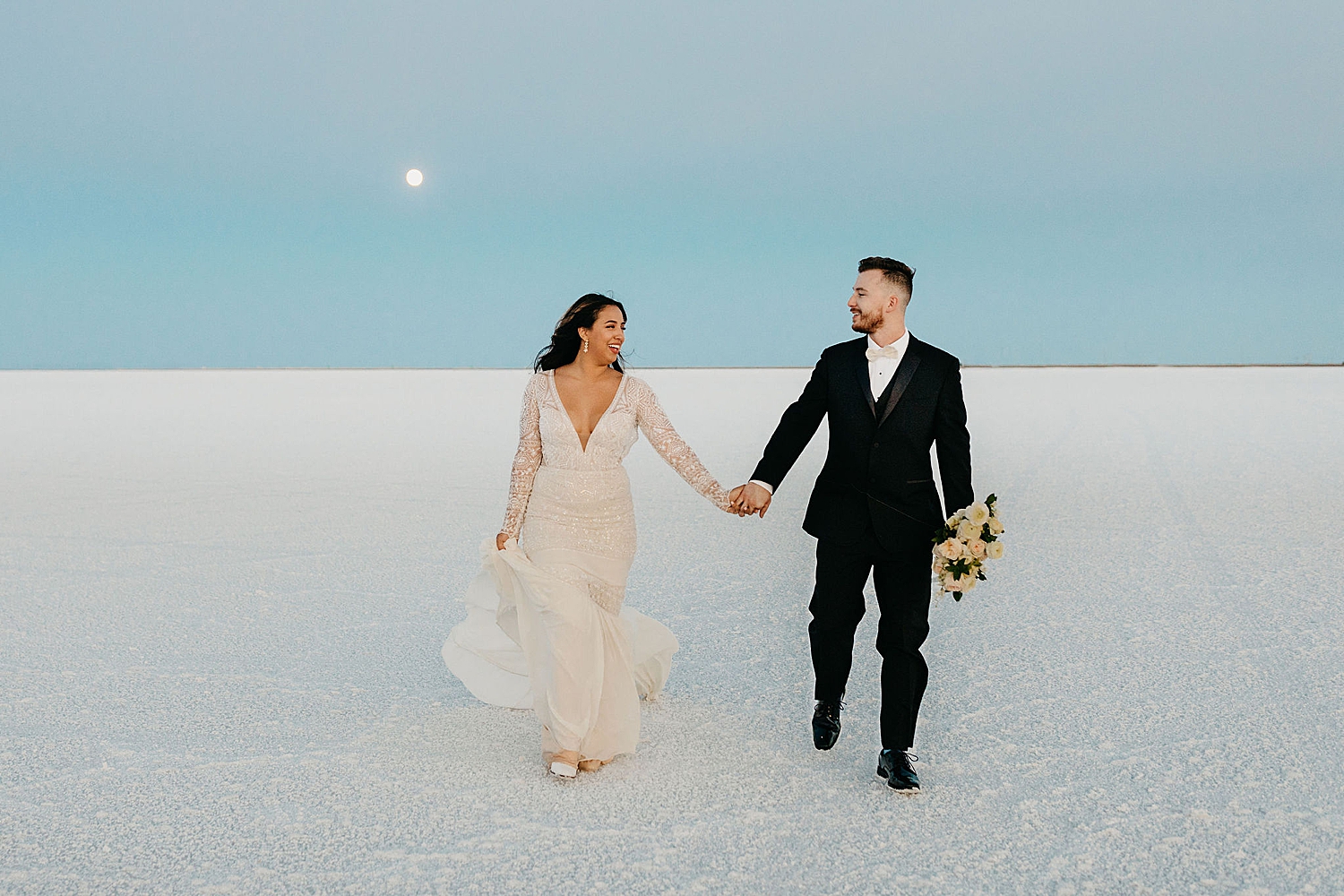 man and woman walk hand in hand under the moon by Nicole Aston Photography
