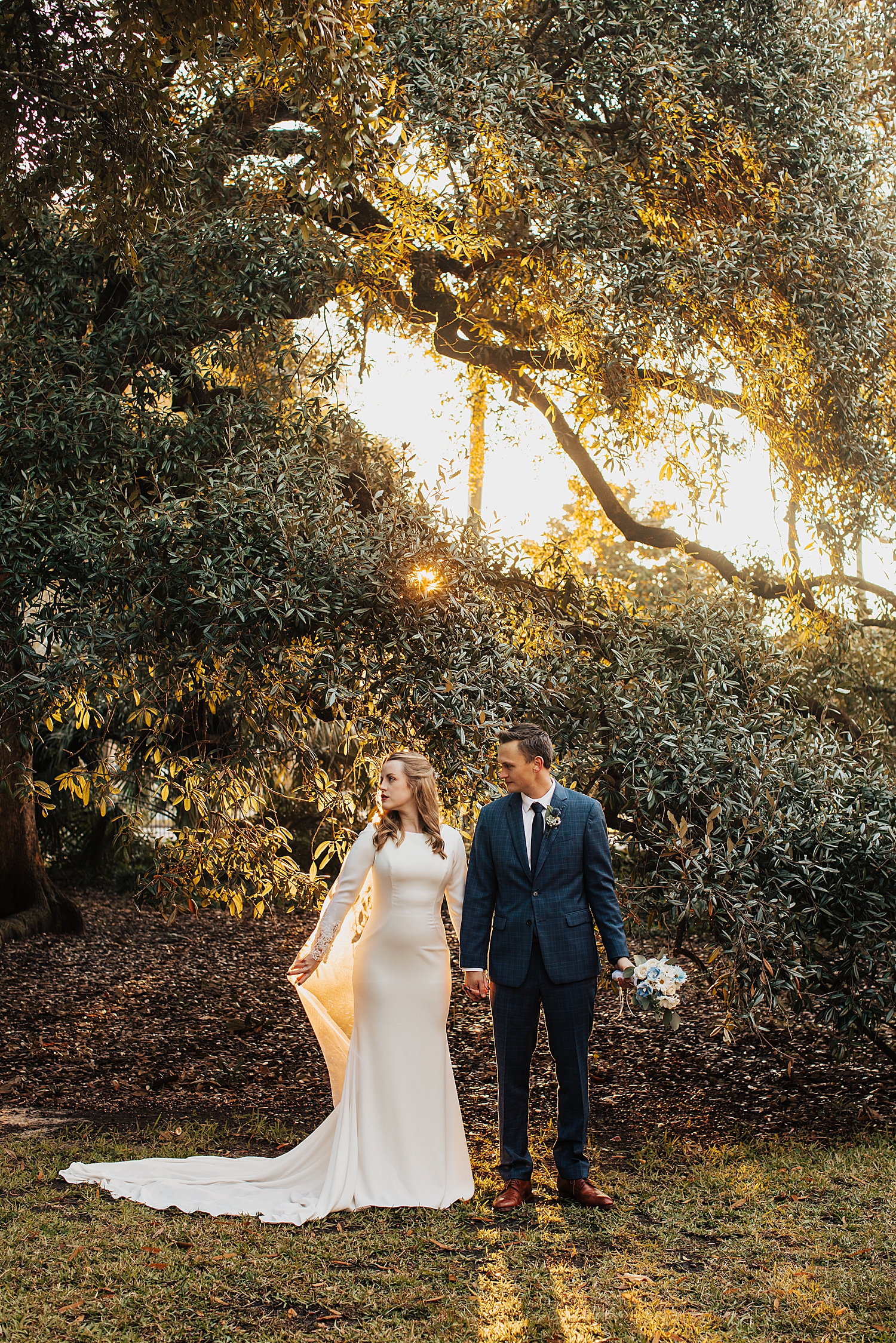 man and woman stand under tree in glowy light by Destination wedding photographer
