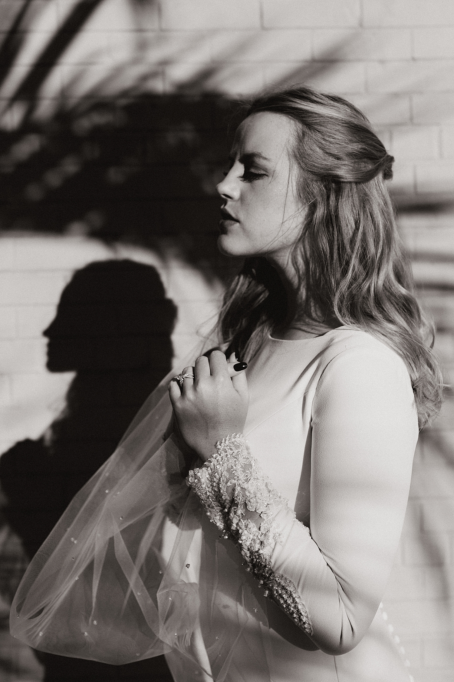 bride stands under palm tree shadows for sunrise shoot