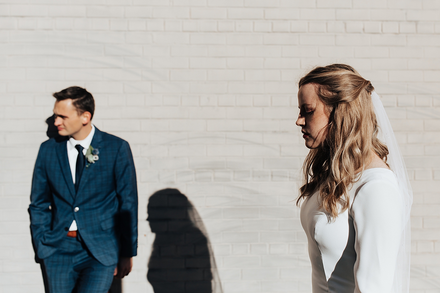 woman in white dress stands near man in blue suit by Nicole Aston Photography