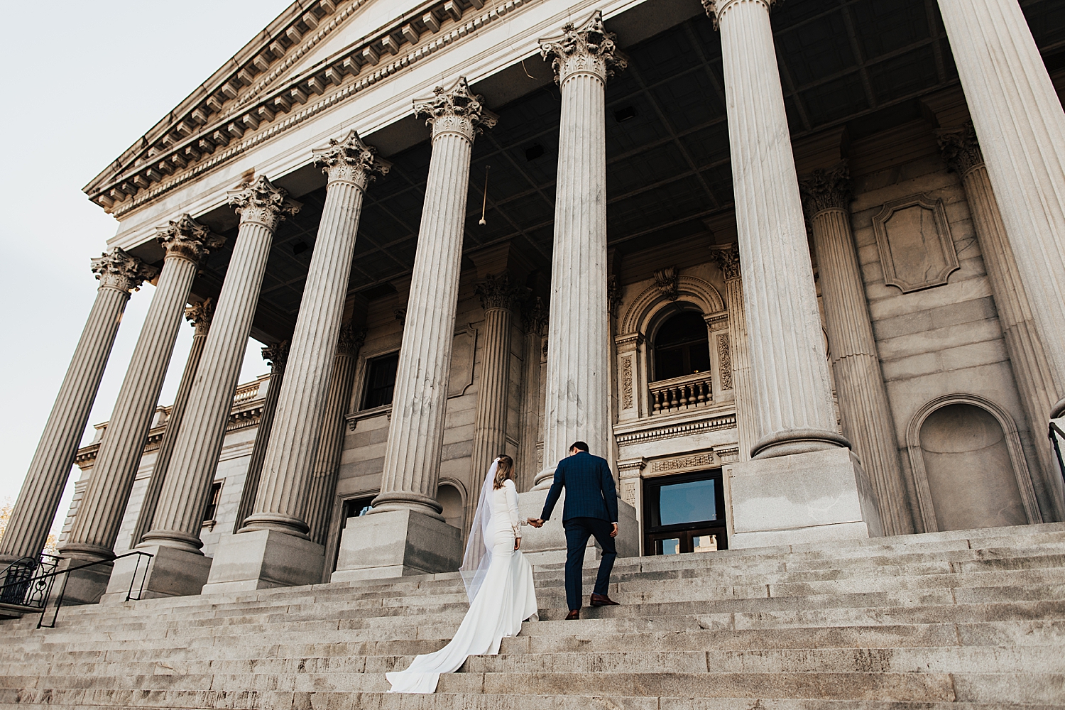 couple walk up ornate staircase in formal wear for sunrise shoot