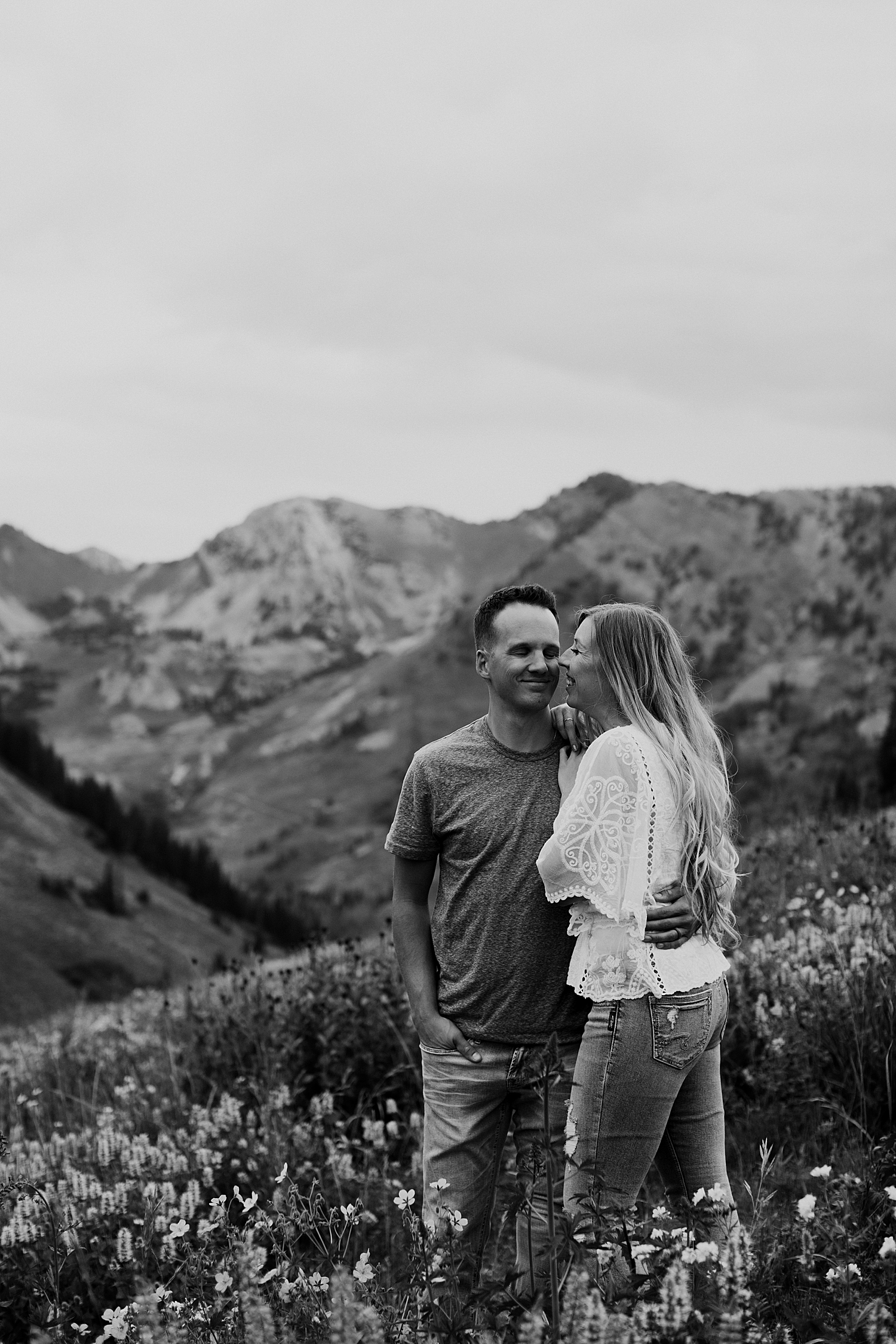 woman leans into her man with mountains as the background by Destination wedding photographer