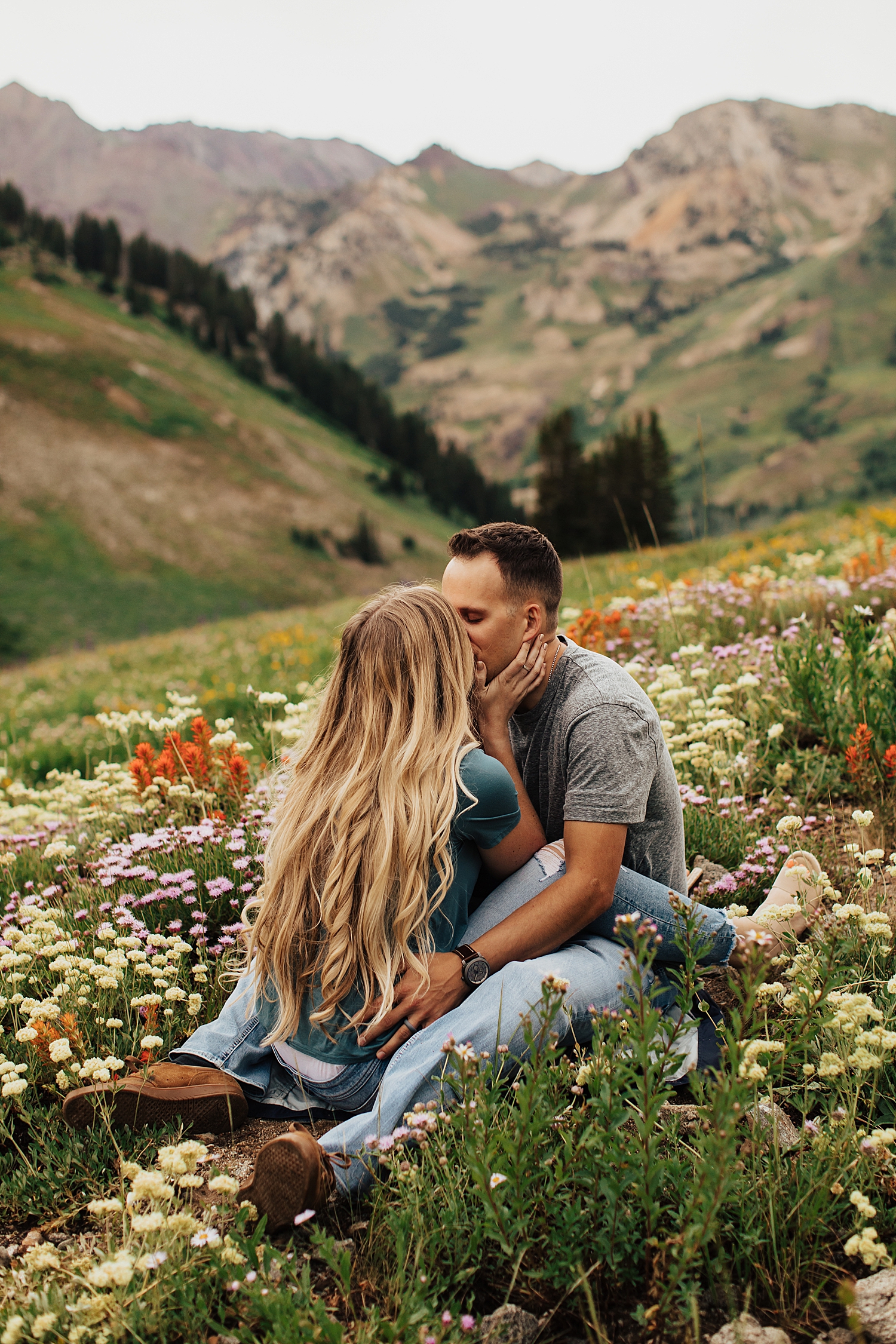 woman and man sit straddled in the middle of florals by Nicole Aston Photography