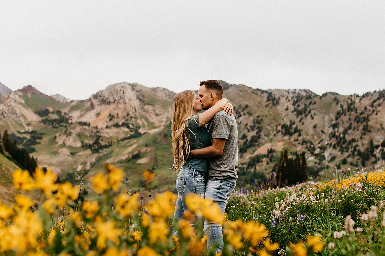 man kisses his wife-to-be around yellow flowers in Albion Basin