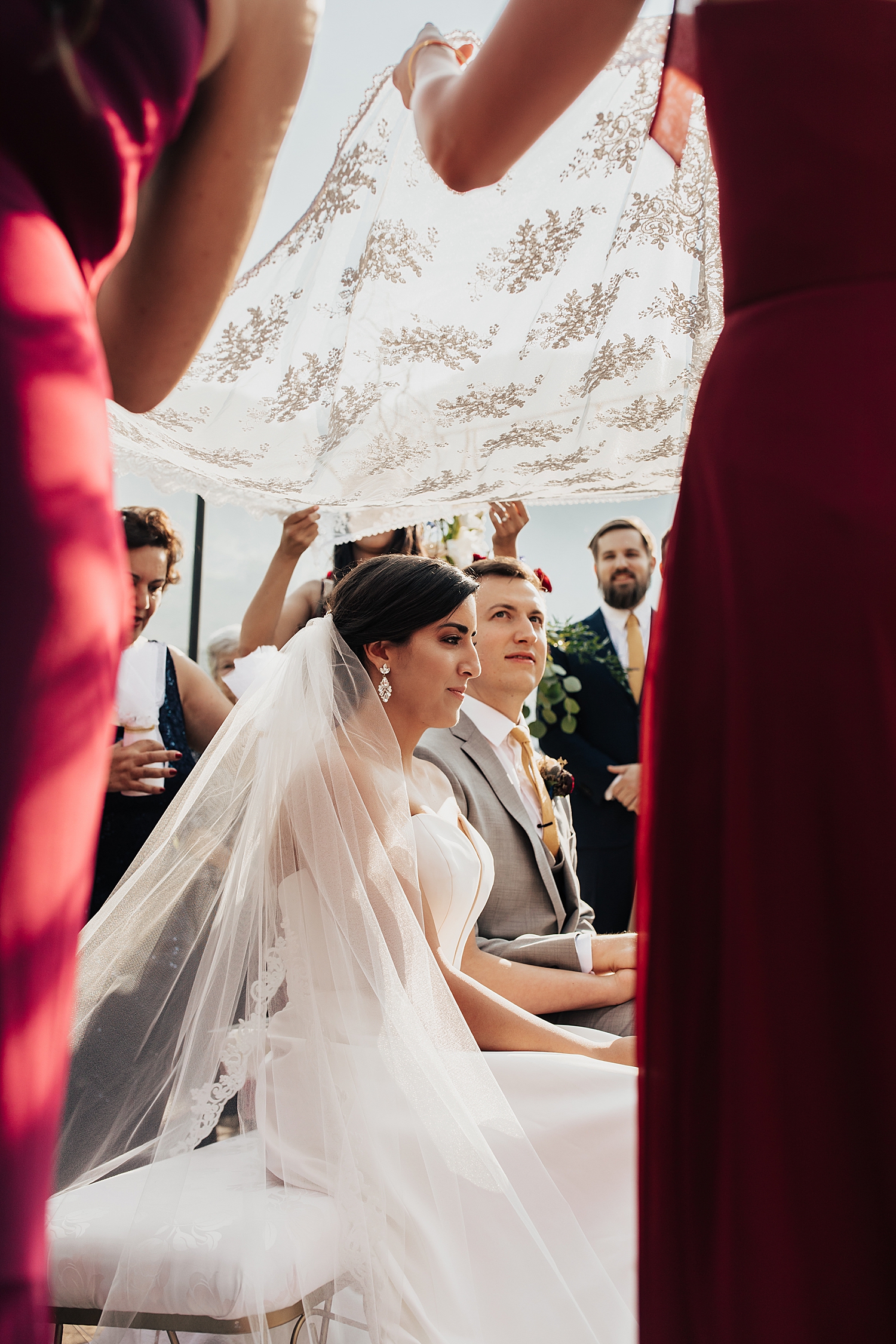man and woman sit under floral cloth for Persian ceremony by Destination wedding photographer