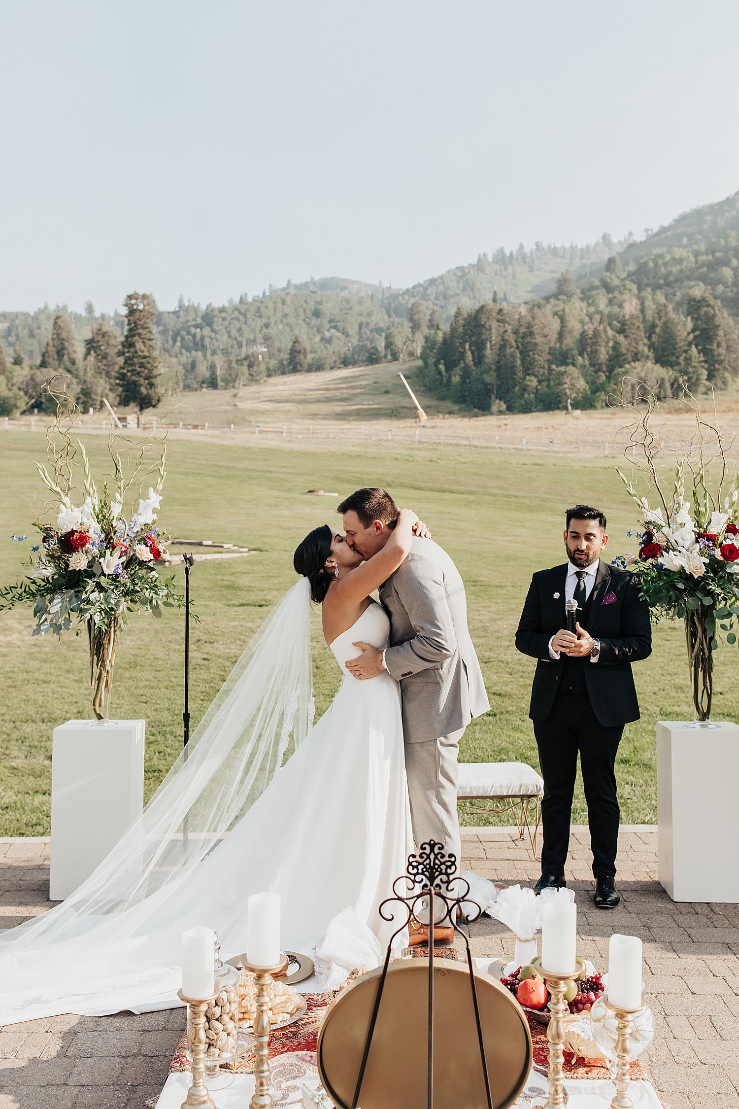 newlyweds share their first kiss at the alter with rolling hills behind them by Nicole Aston Photography