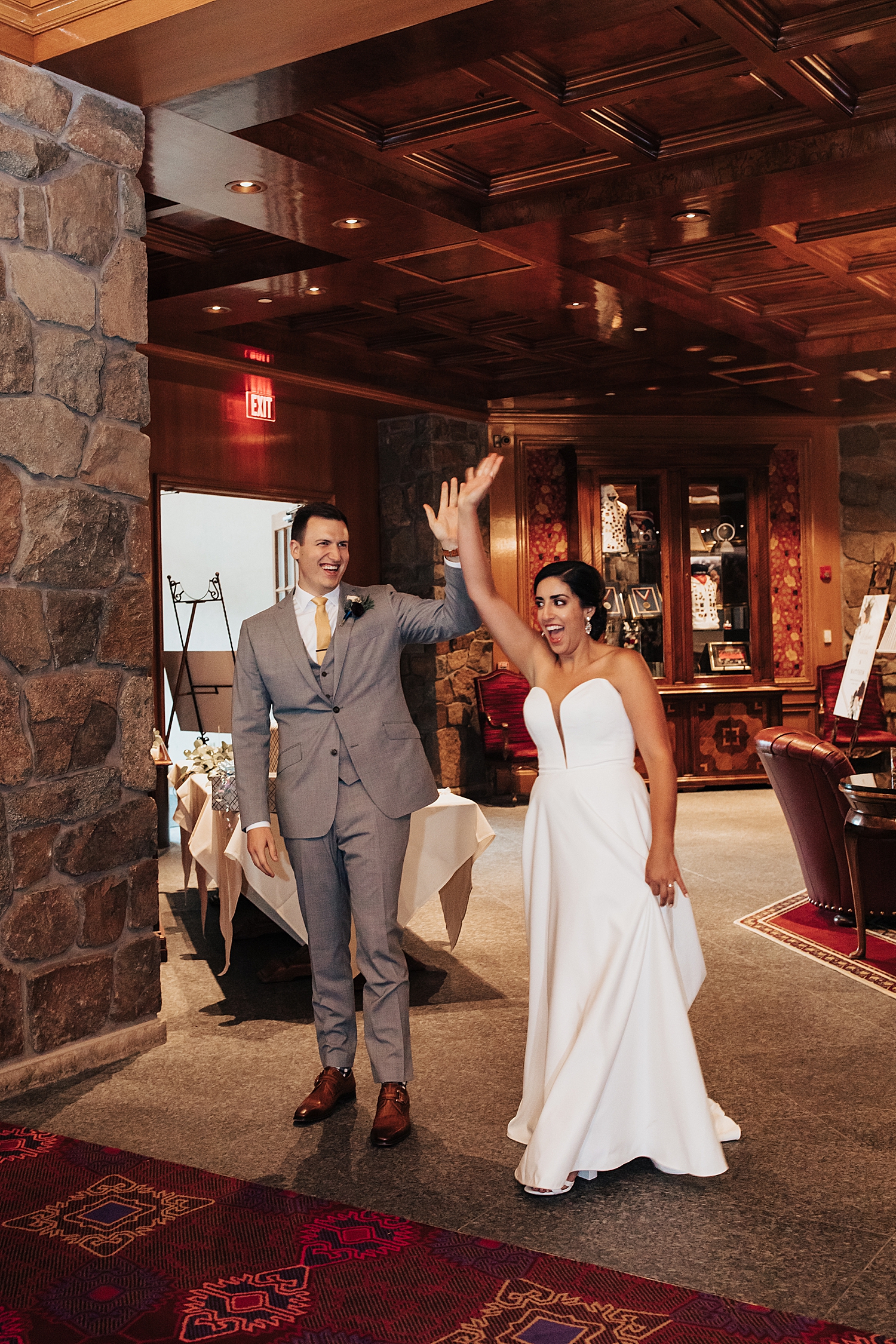 newlyweds enter their reception with their hands in the air by Nicole Aston Photography