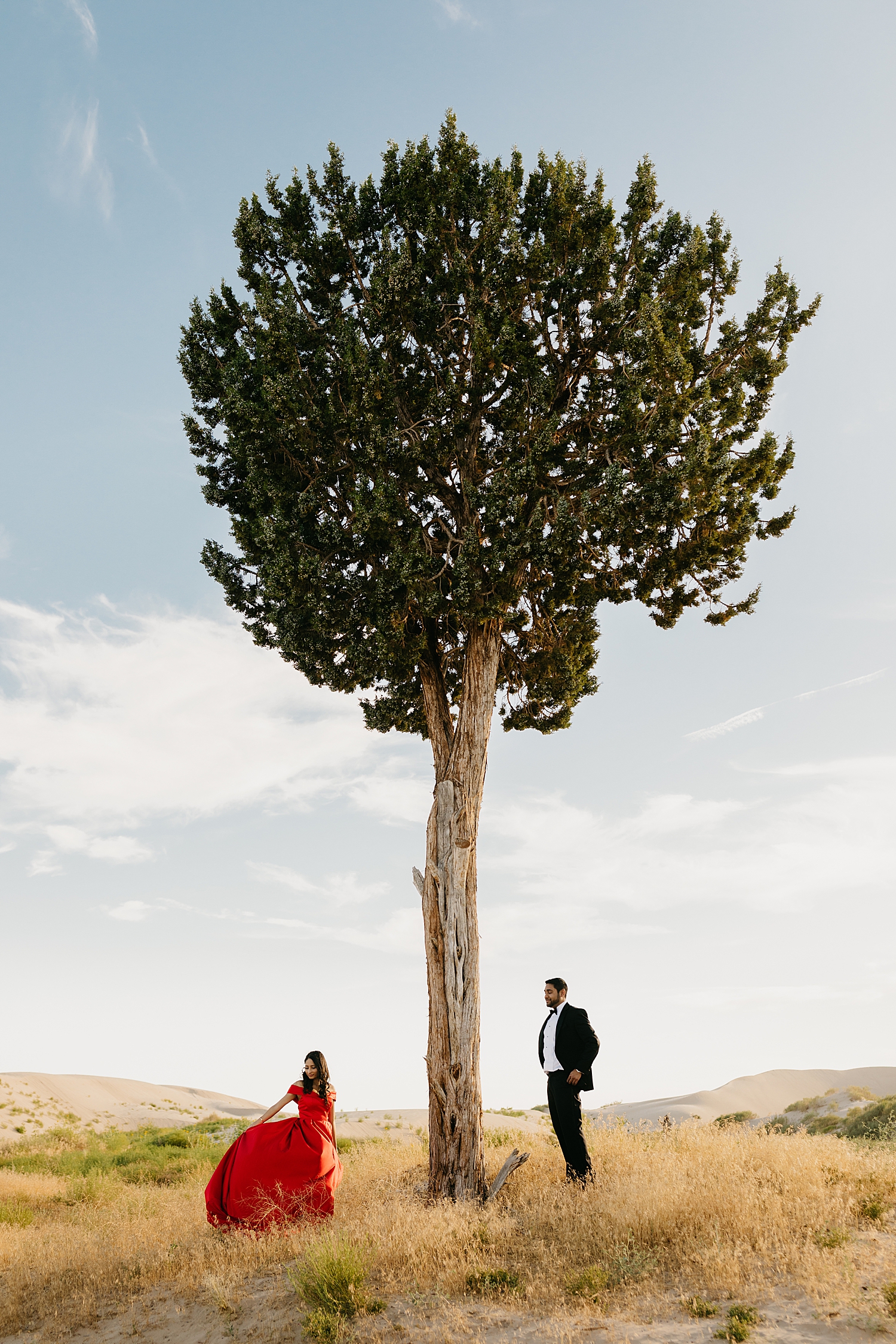 couple stand next to tall tree in formal wear by Destination wedding photographer 