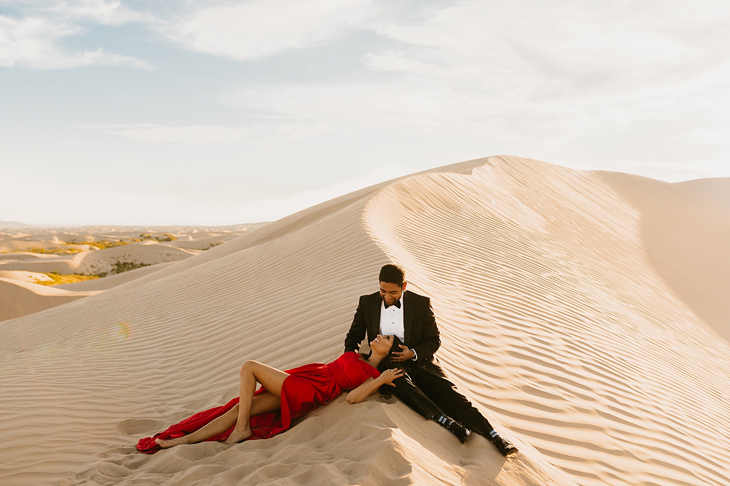 woman lies her head in mans lap while lying on sandy hill by Nicole Aston Photography