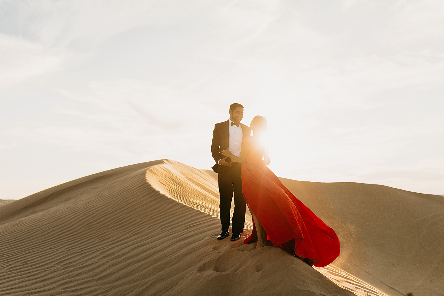 engaged couple embrace in golden hour lighting for Sand Dune engagement session