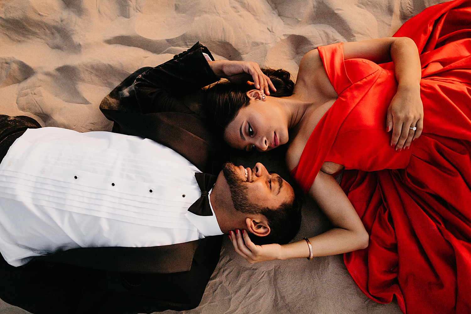 man and woman lie on ground facing each other by Nicole Aston Photography