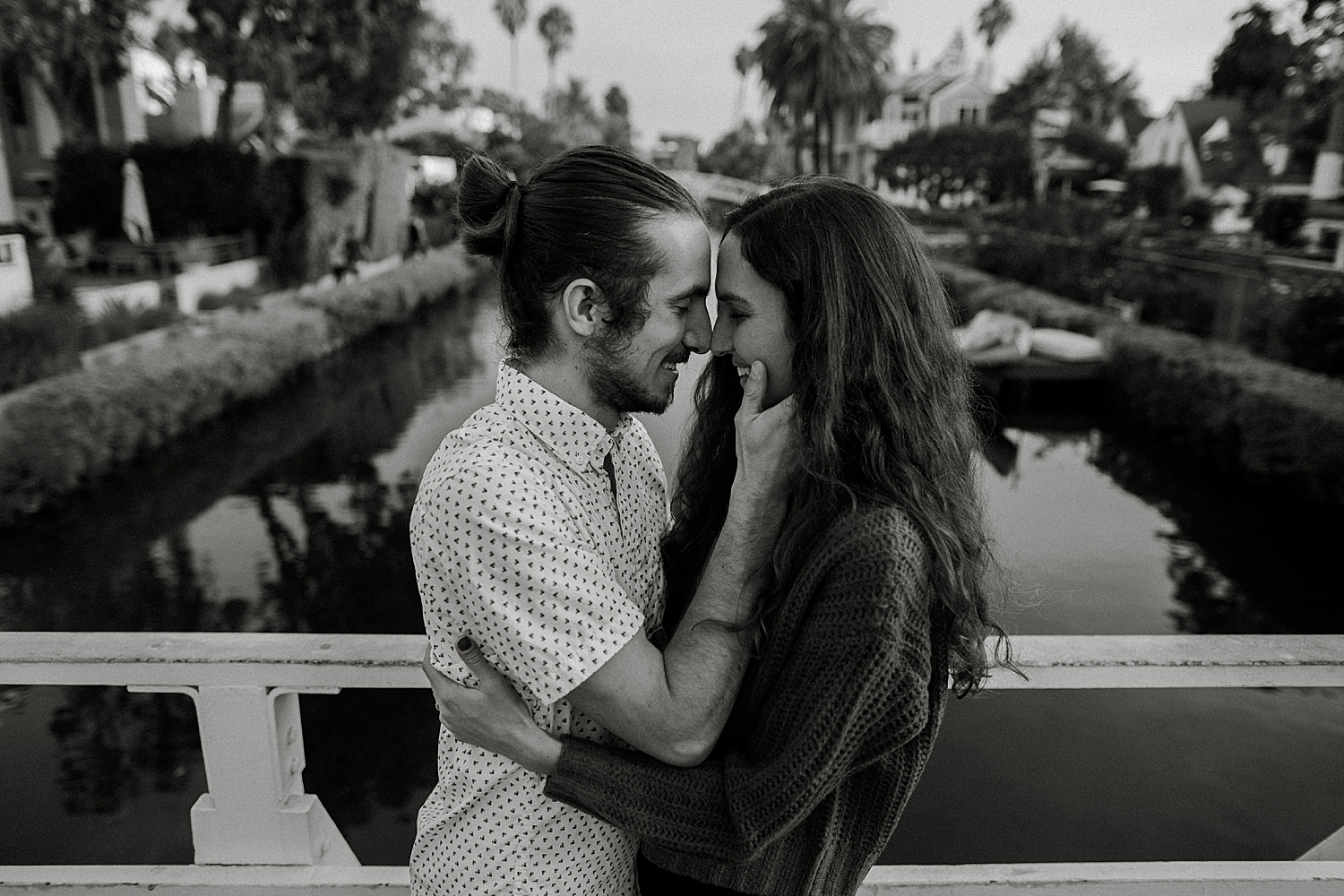 two people lean together for a kiss under palm trees by Nicole Aston Photography