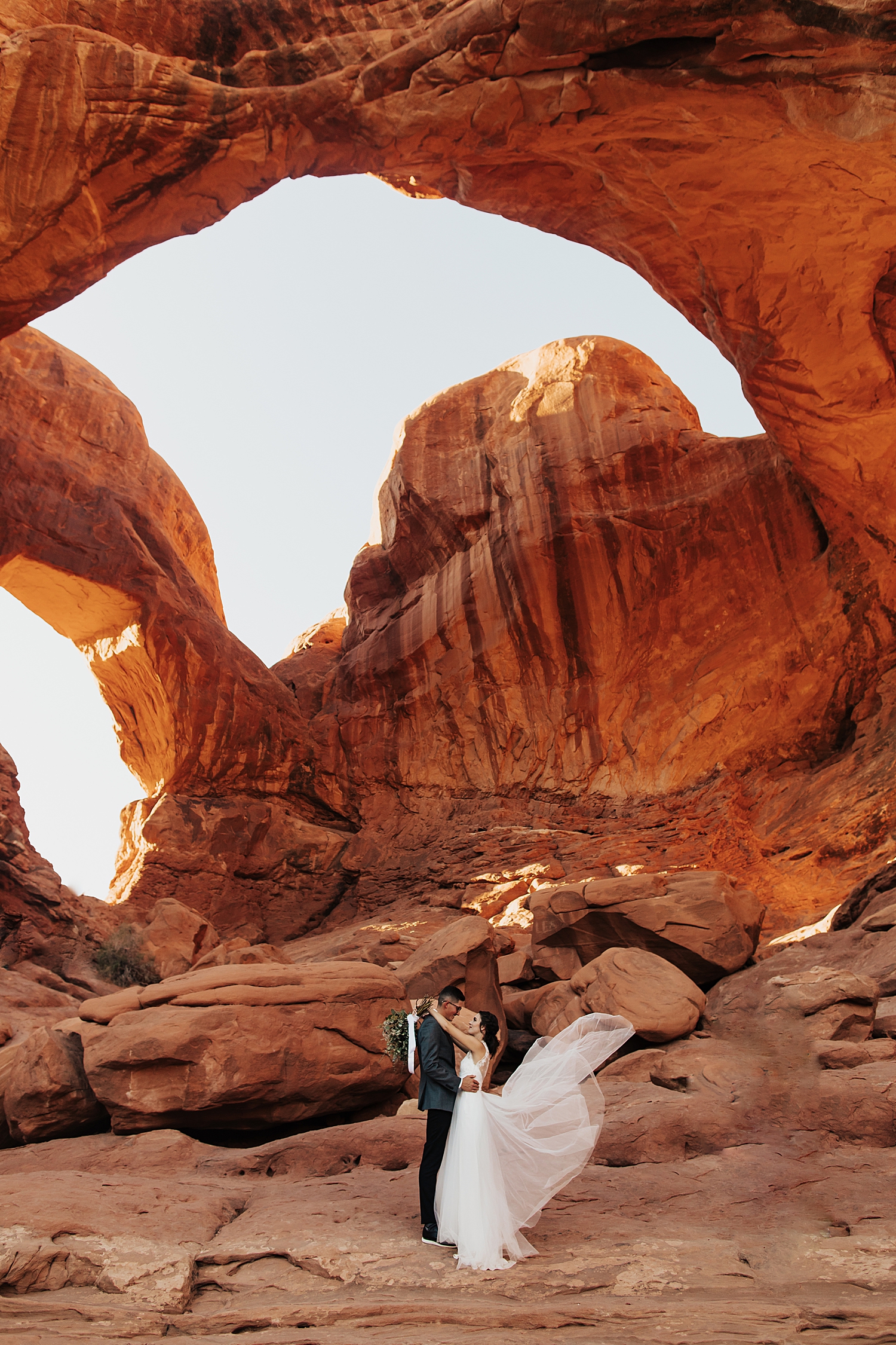 newlyweds share a kiss while brides dress floats in the wind by Nicole Aston Photography