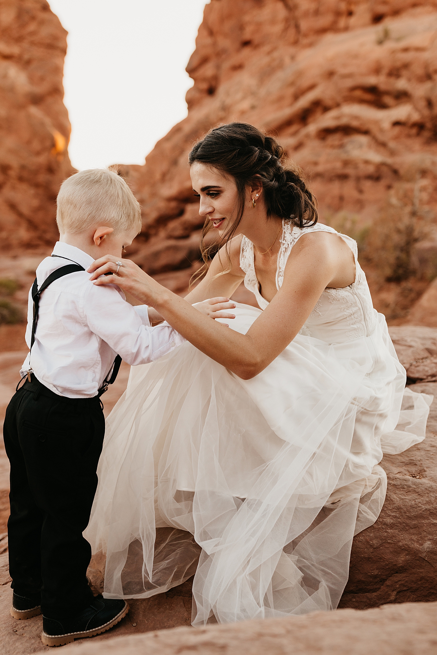 mama in bridal gown fixes her toddler's suspenders for Moab wedding portraits