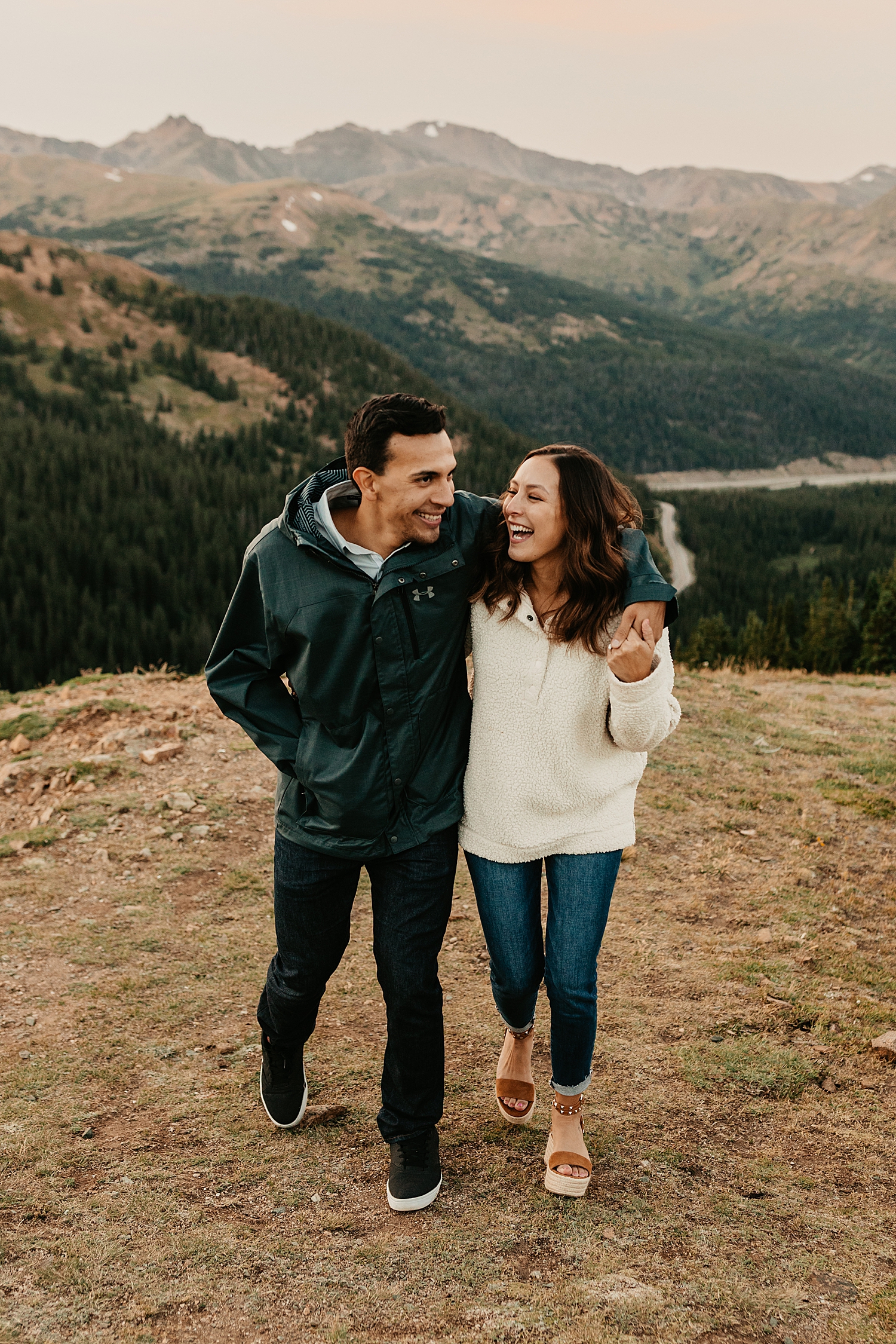 couple in jackets laugh as they walk together in colorado by Nicole Aston Photography