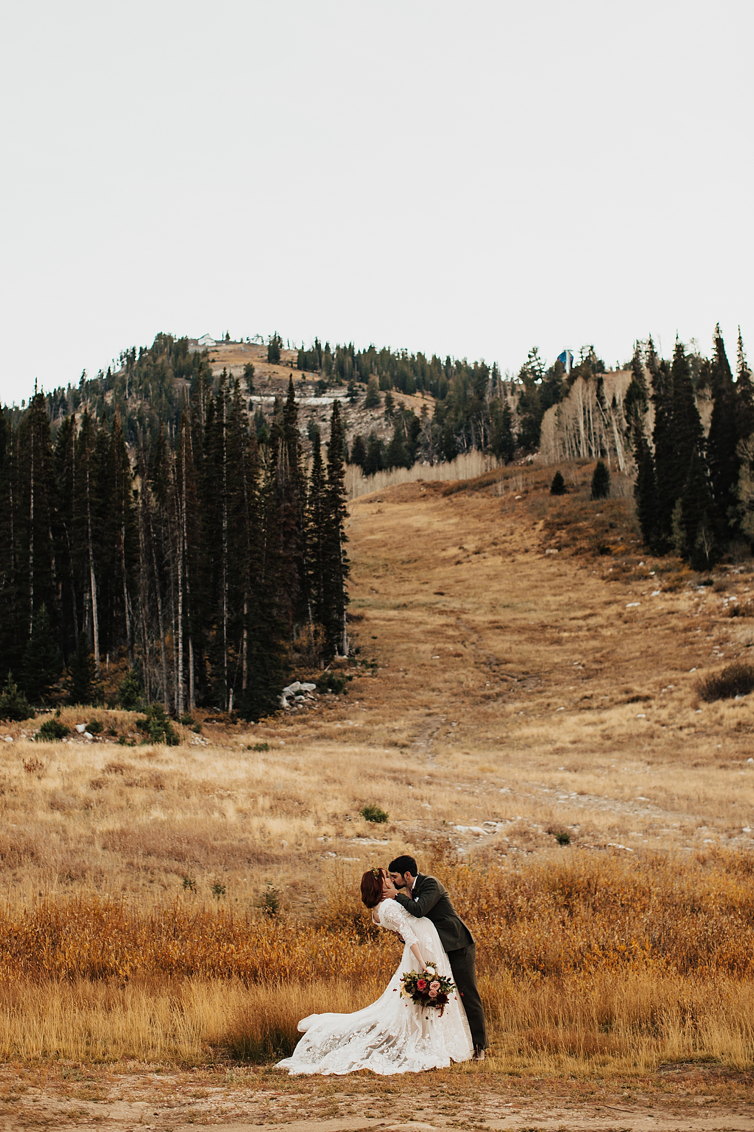 man dips his new wife for a kiss in a big field at Solitude Resort in Park City