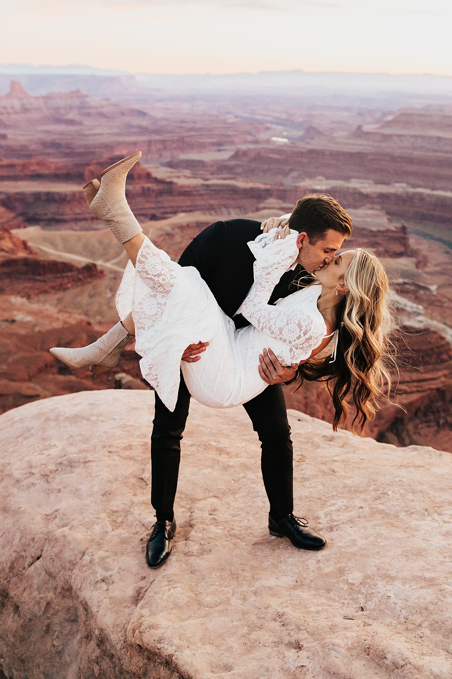 newlyweds dip for a kiss overlooking canyon by Nicole Aston Photography