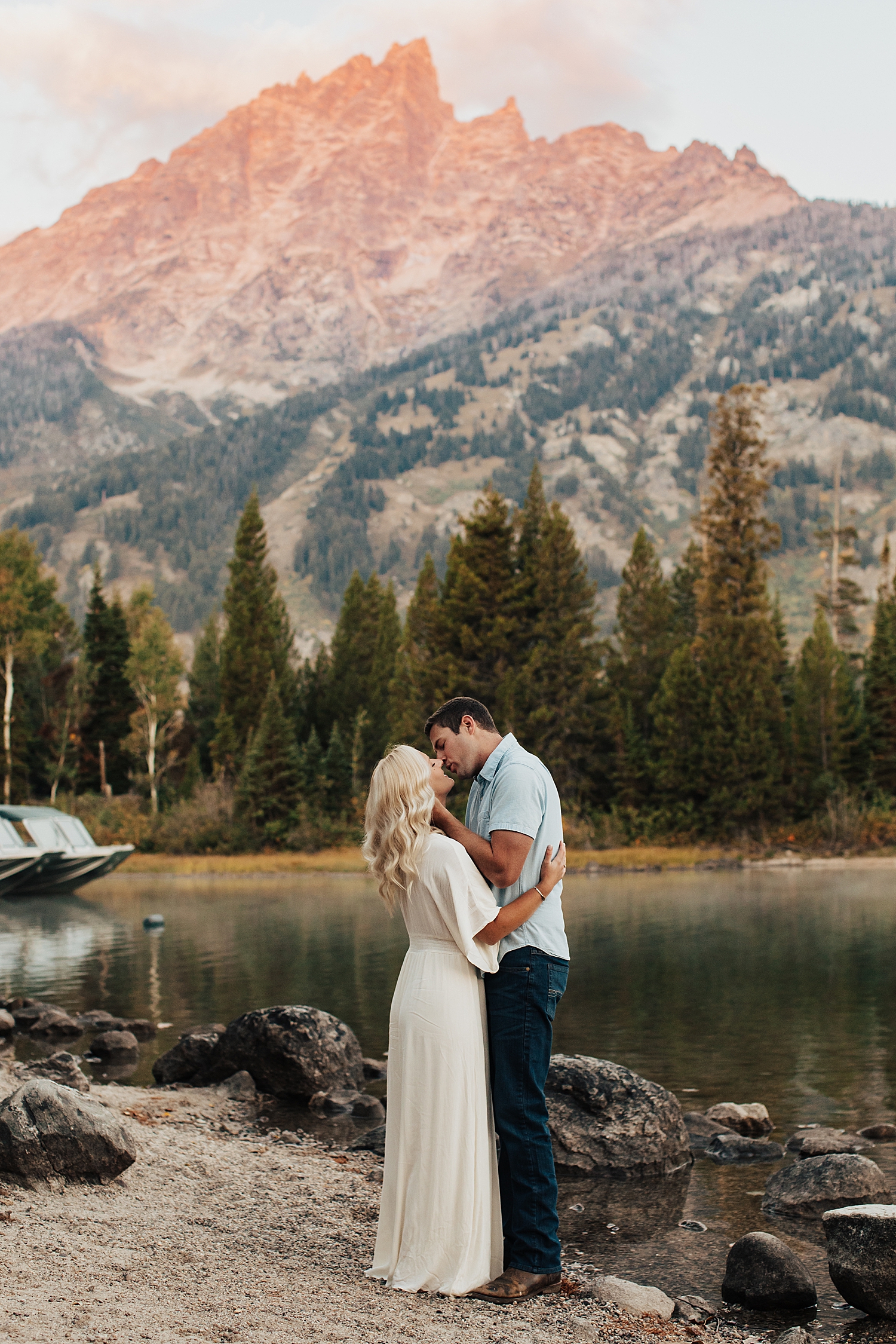 husband reaches in to hold wife's face for a kiss in front of mountain by Nicole Aston Photography