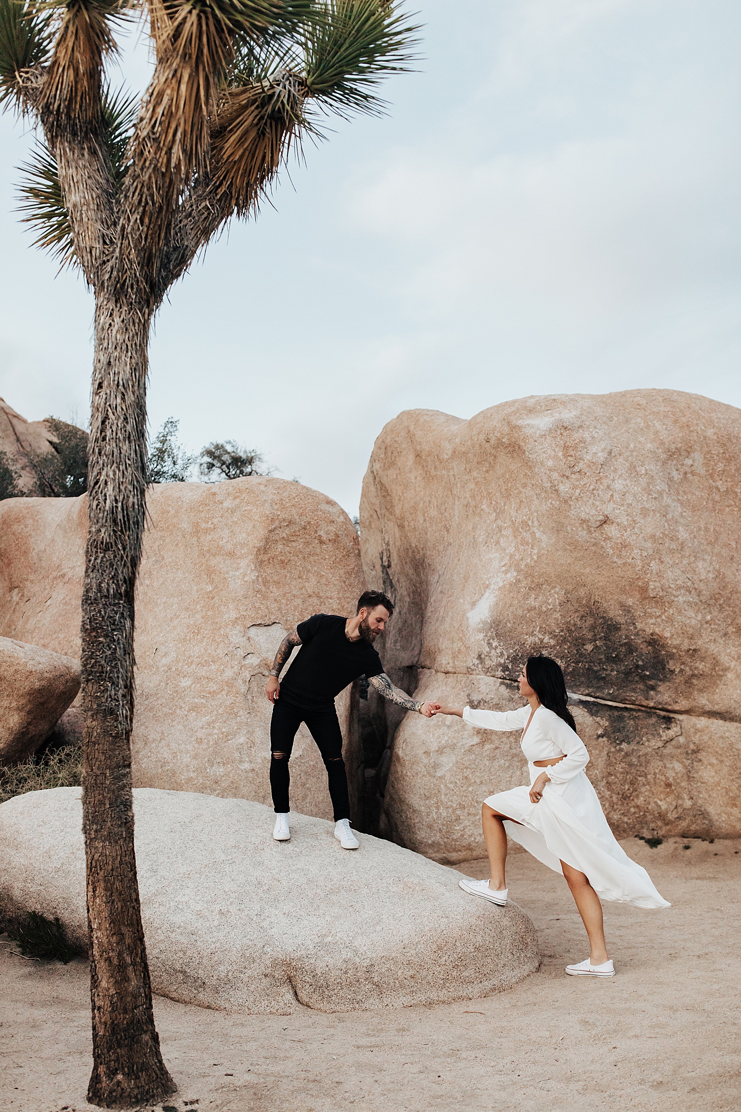 man on rock reaches back to help woman up by Destination wedding photographer