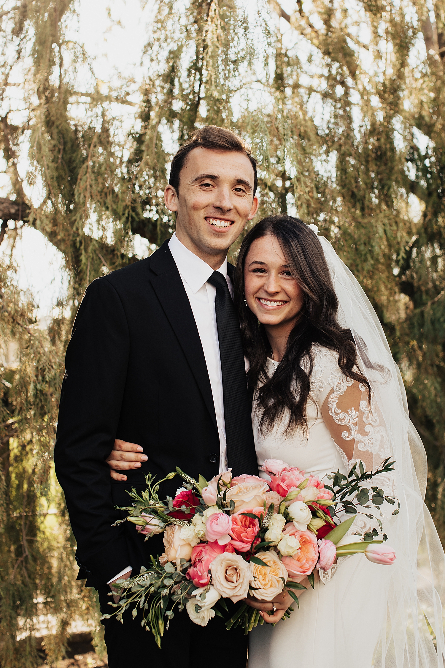 man and woman hug closely under willow tree by Nicole Aston Photography