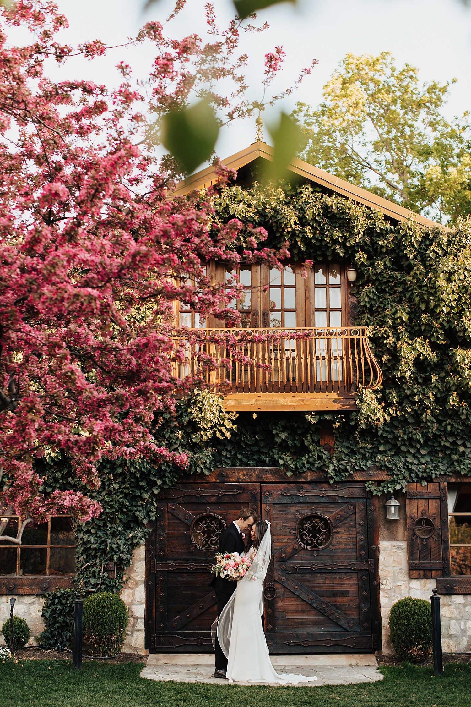 bride and groom hug in front of wooden barn doors by Nicole Aston Photography
