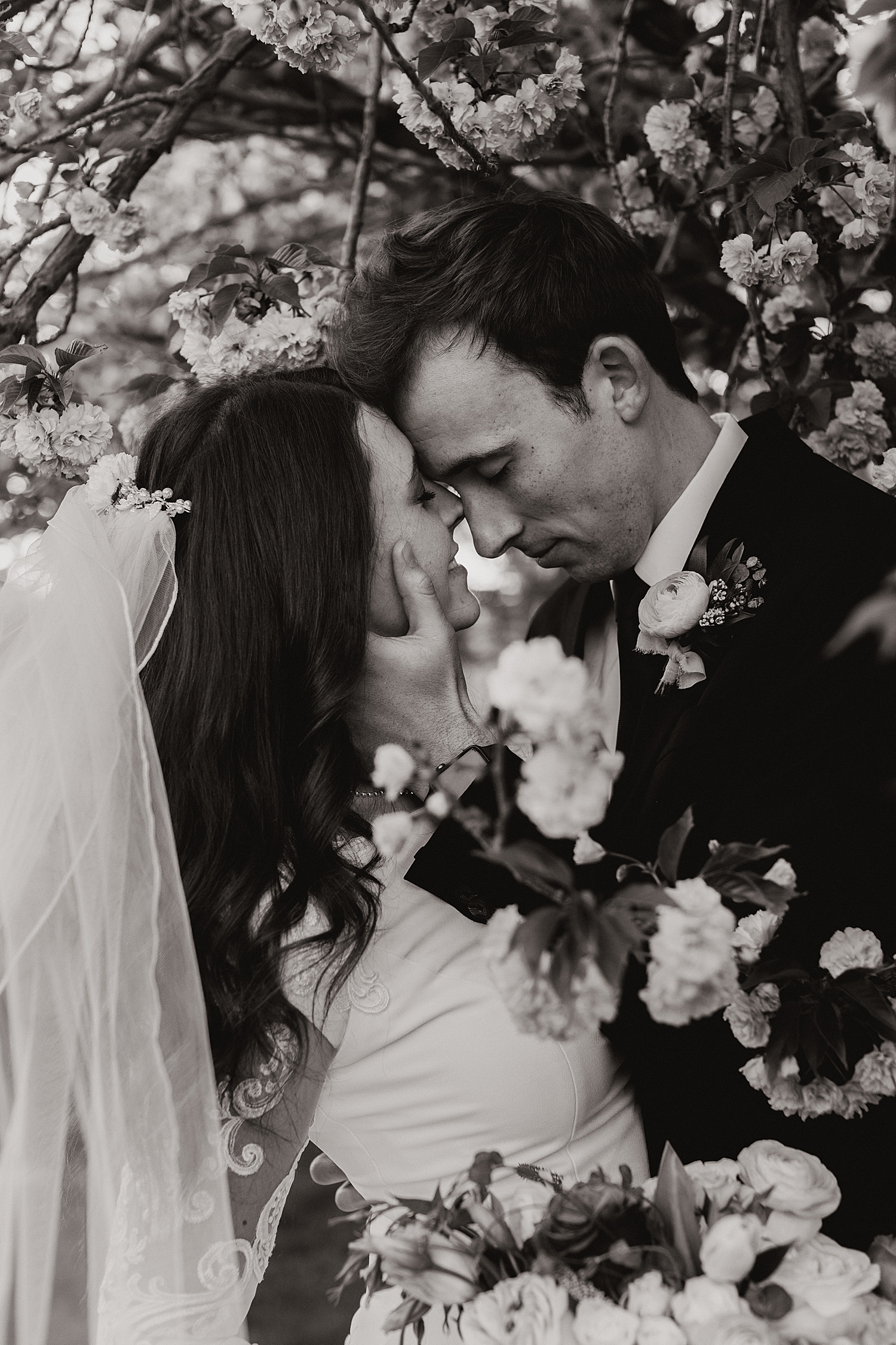 man holds woman's face in his large hands in the flowers by Nicole Aston Photography
