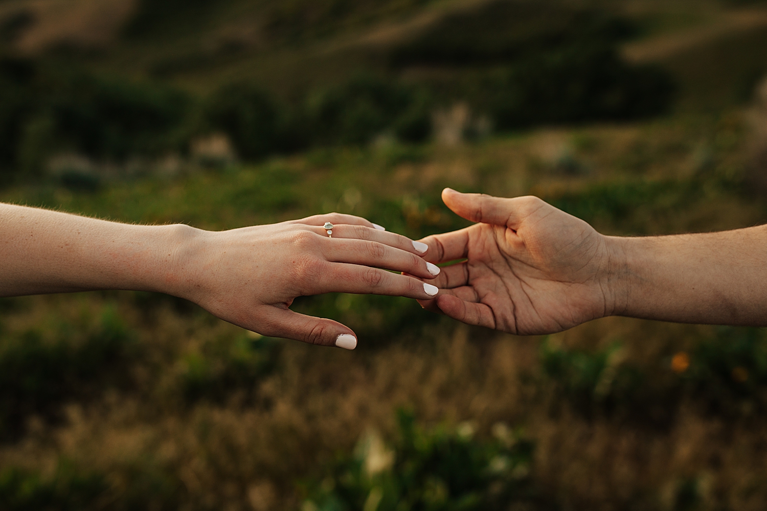 couple holds hands outside, showing off diamond ring by Destination wedding photographer