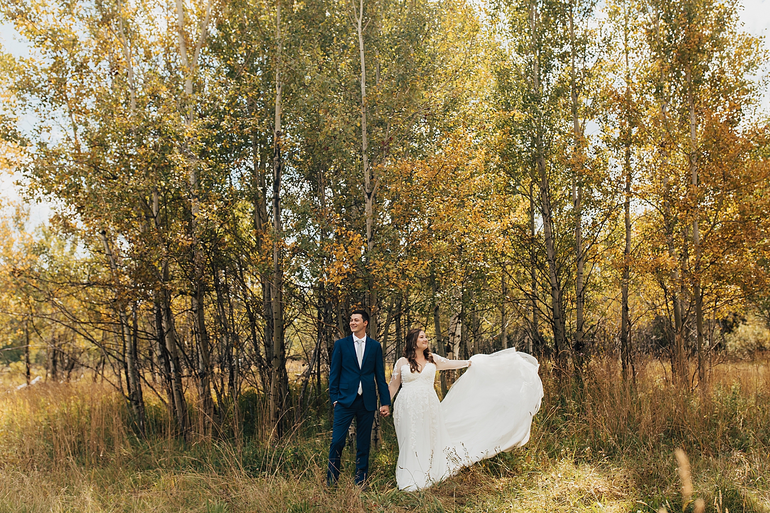 man and woman stand under golden trees by Destination wedding photographer