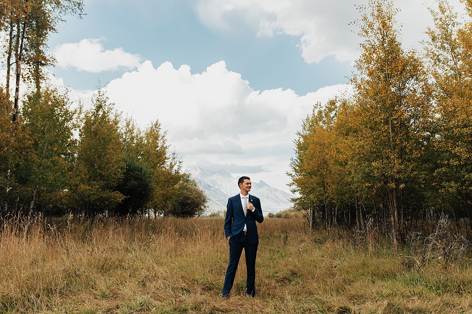man in blue suit stands in front of mountains at Snake River Ranch