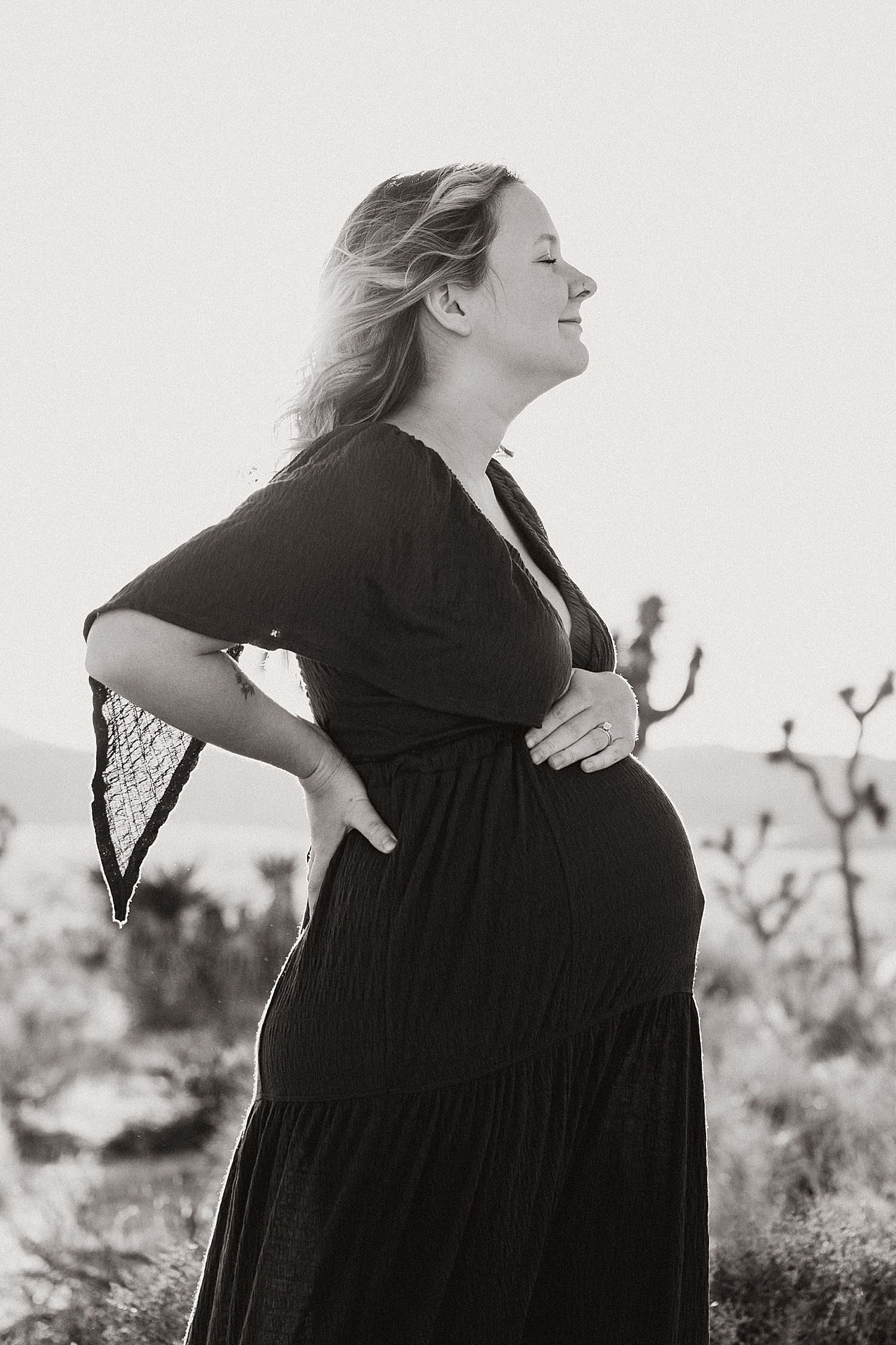 mama cradles her belly outside for Maternity Photos at Joshua Tree