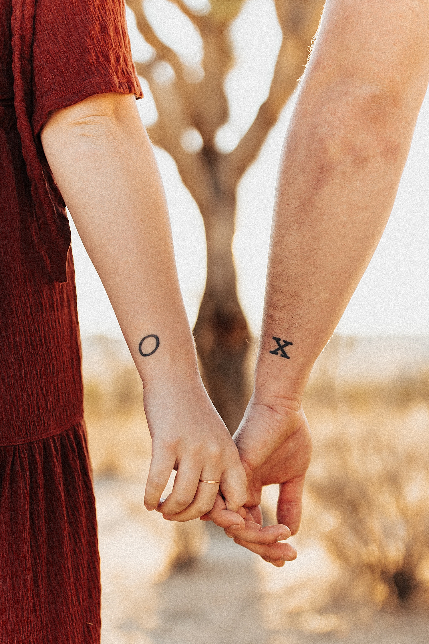 married couple holds hands with matching tattoos for Maternity Photos at Joshua Tree