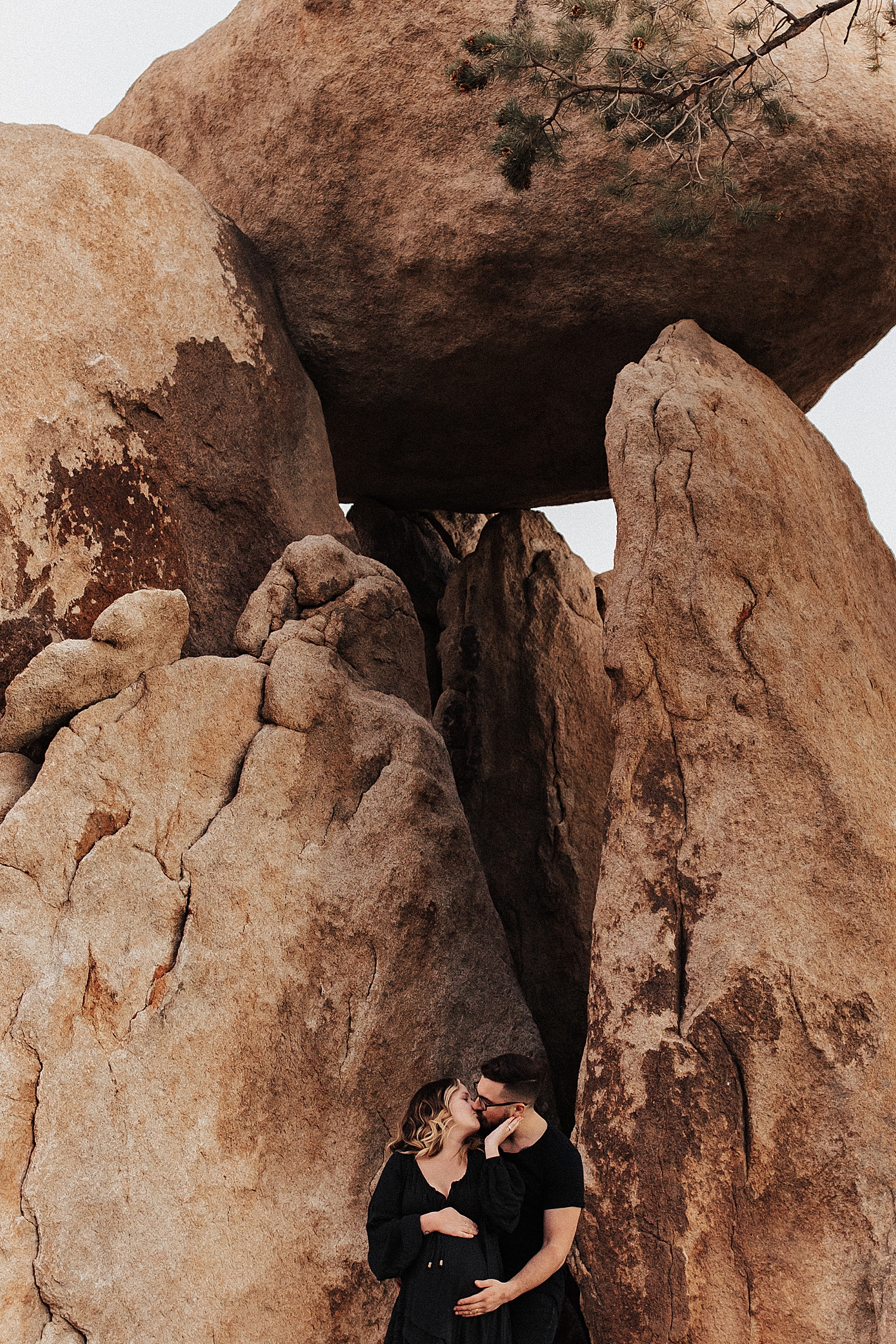 couple share a kiss under large rocks by Destination wedding photographer