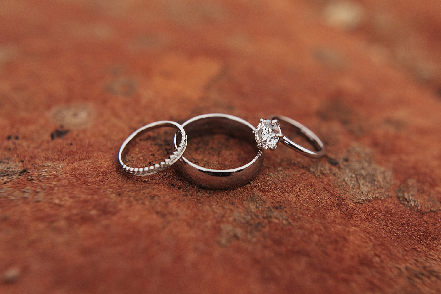 three rings sit on burnt orange rock by Destination wedding photographer