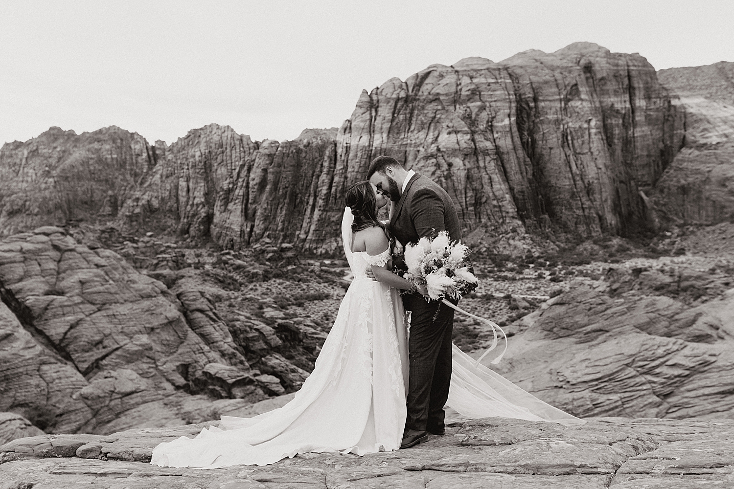 husband and wife share a kiss in front of Utah landscape by Nicole Aston Photography