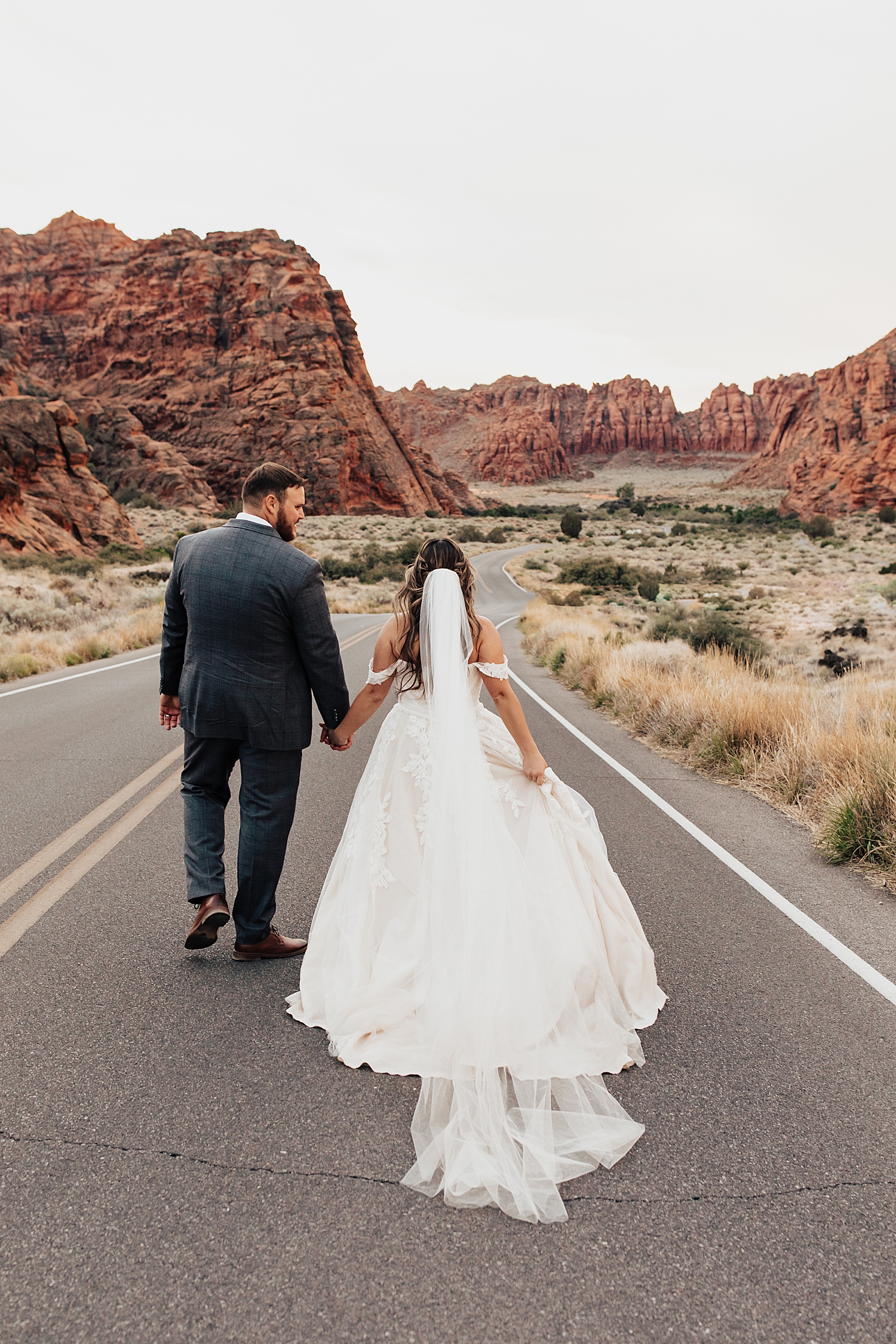 new husband and wife walk down road at Snow Canyon