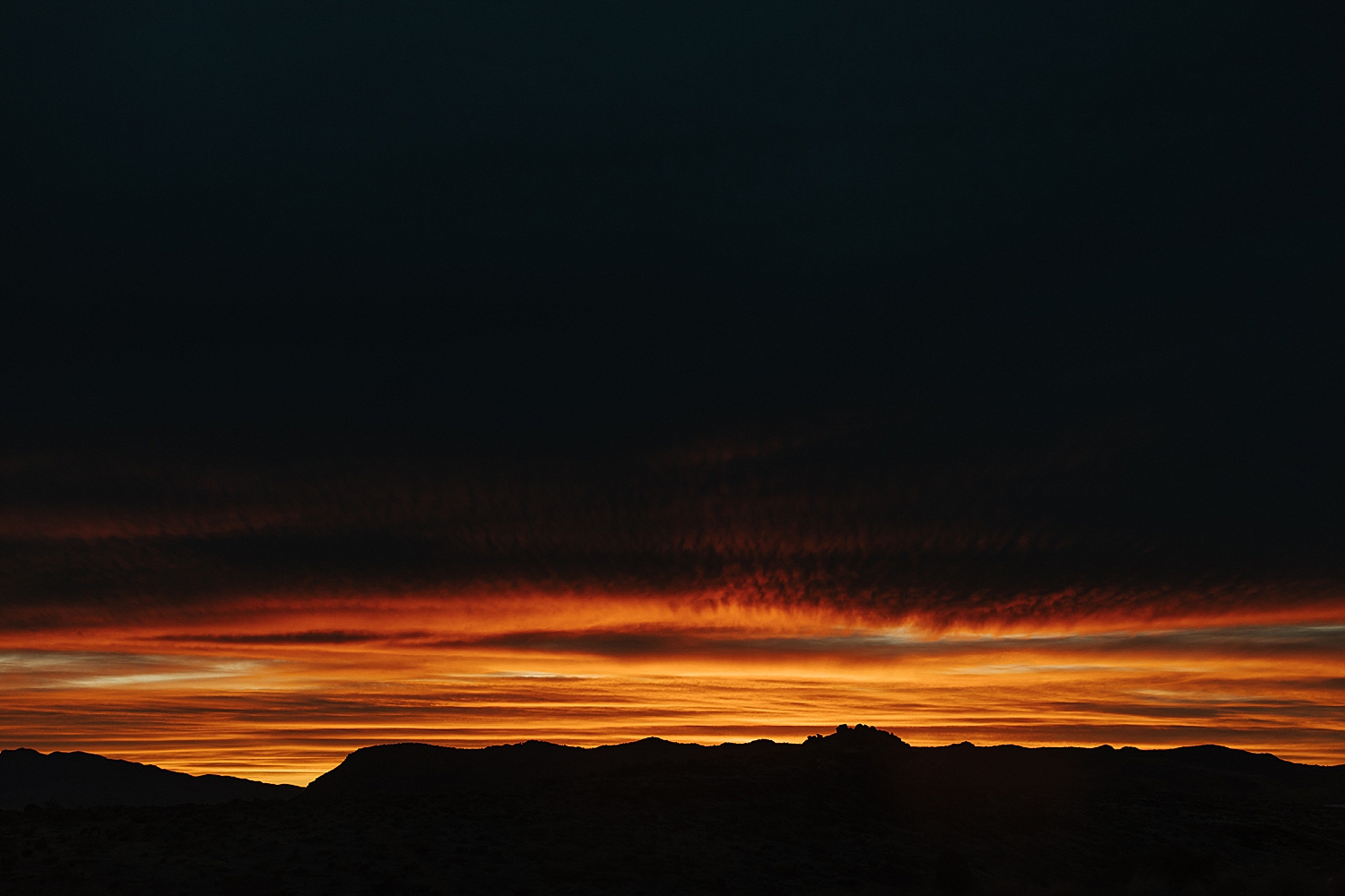 deep setting sun with orange glow on clouds in Utah by Nicole Aston Photography