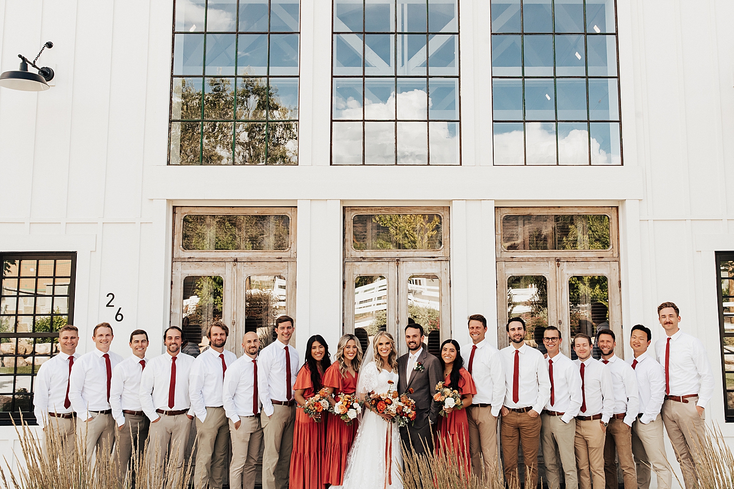 bridal party in coral and tan stand in front Walker Farms