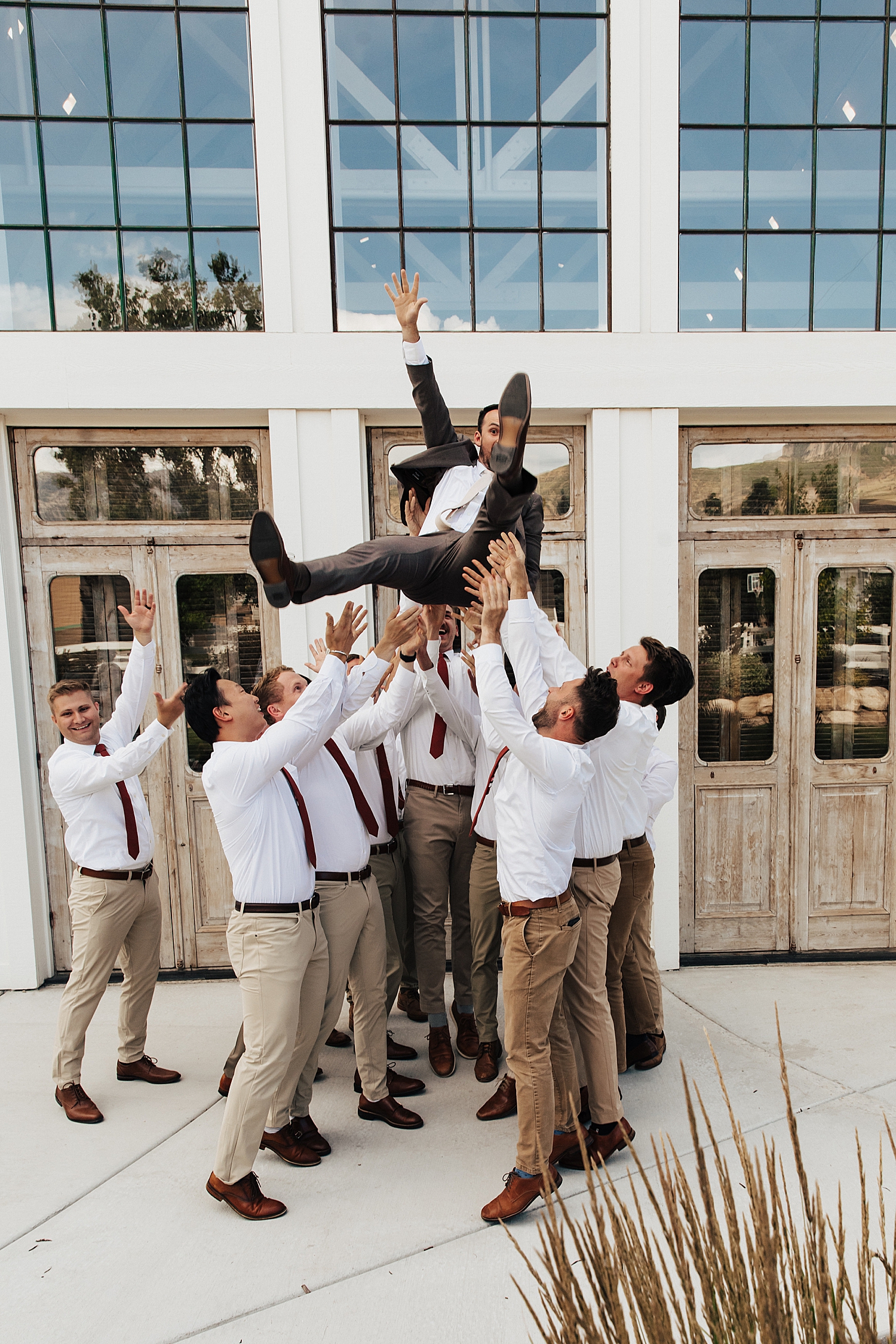 groomsmen throw groom in the air by Destination wedding photographer